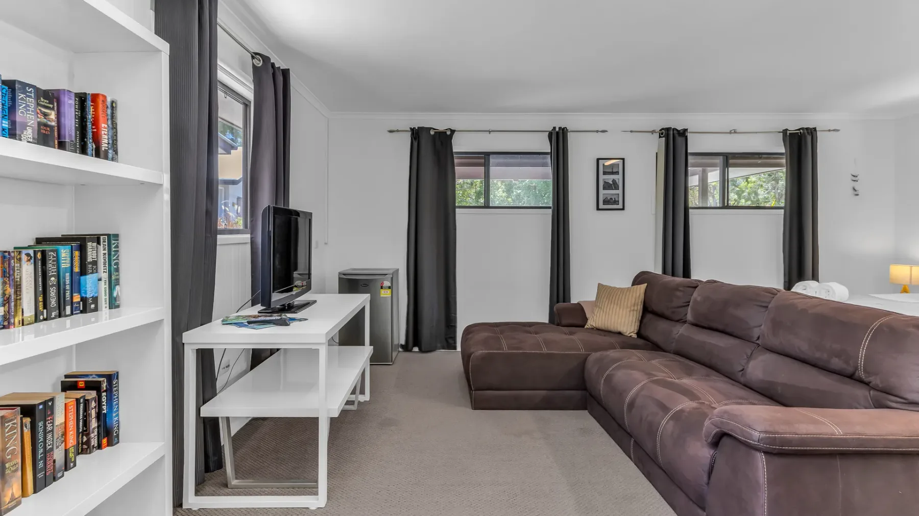 A living room with a large sectional sofa, a television, and bookshelves.