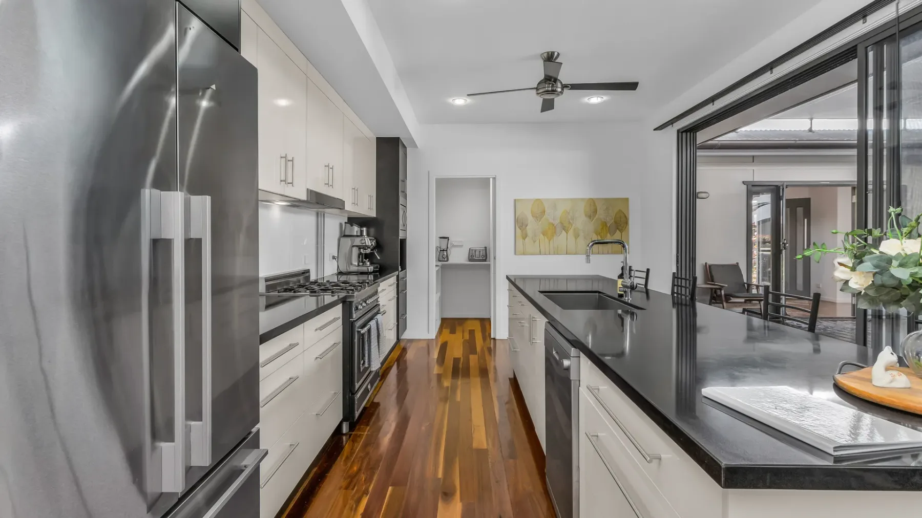 A modern kitchen with dark countertops opens onto a dining area.