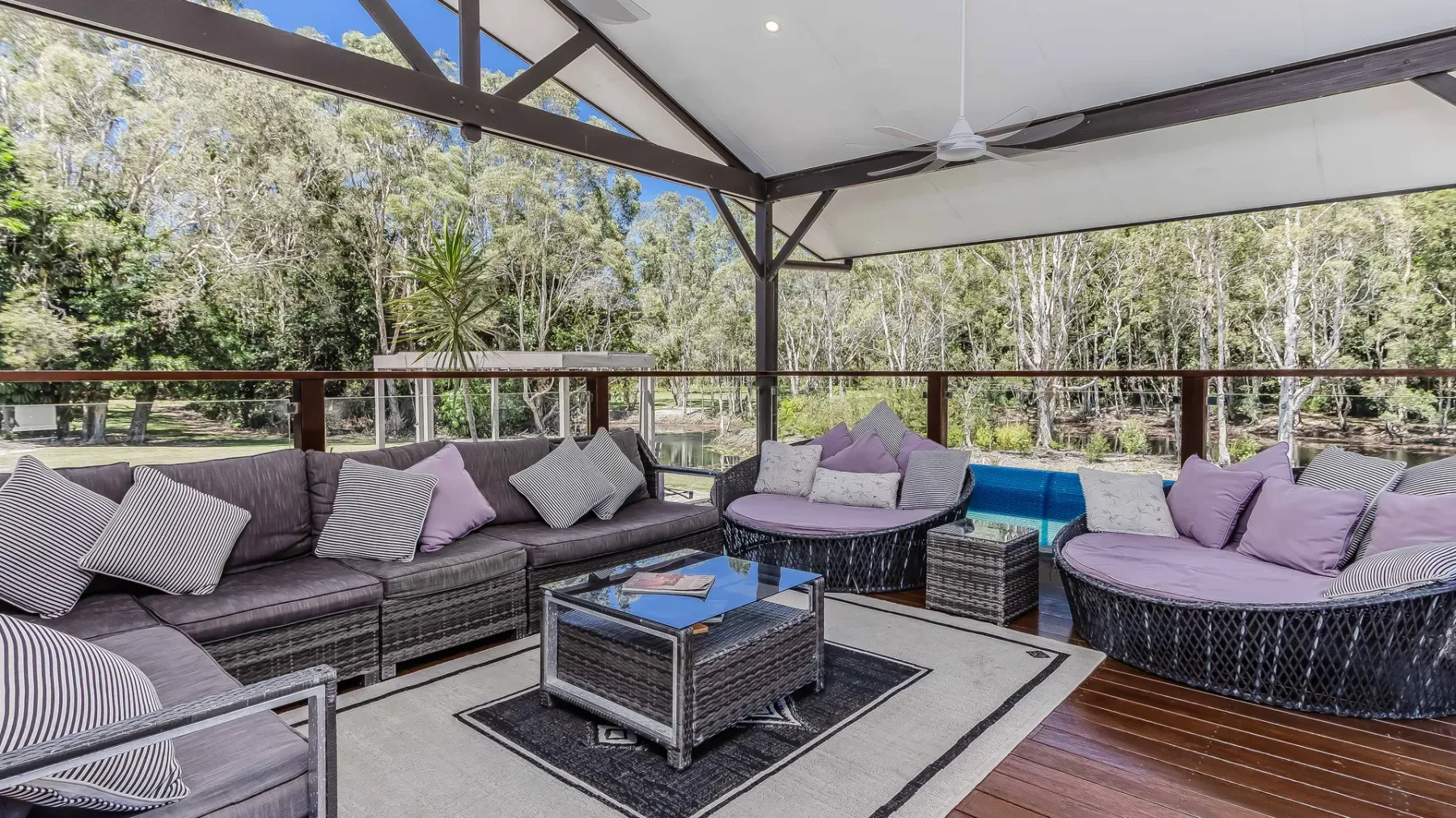 A covered outdoor seating area with cushioned lounge seating and a low table.