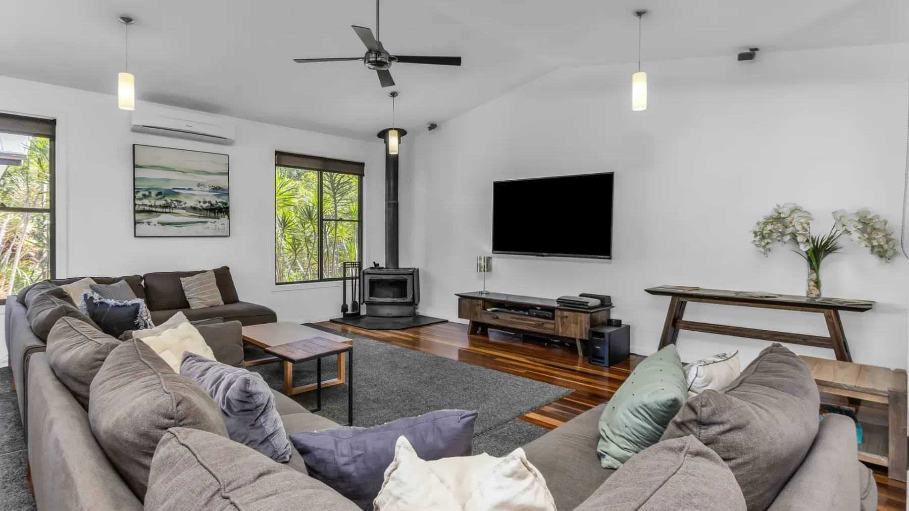 A living room with seating arranged around a television and a small stove.