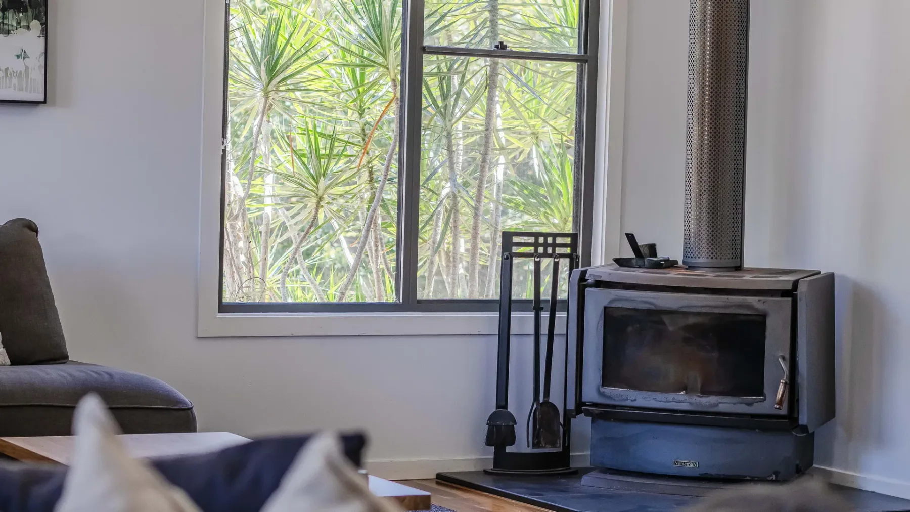 A living room with a wood-burning stove beside a large window.