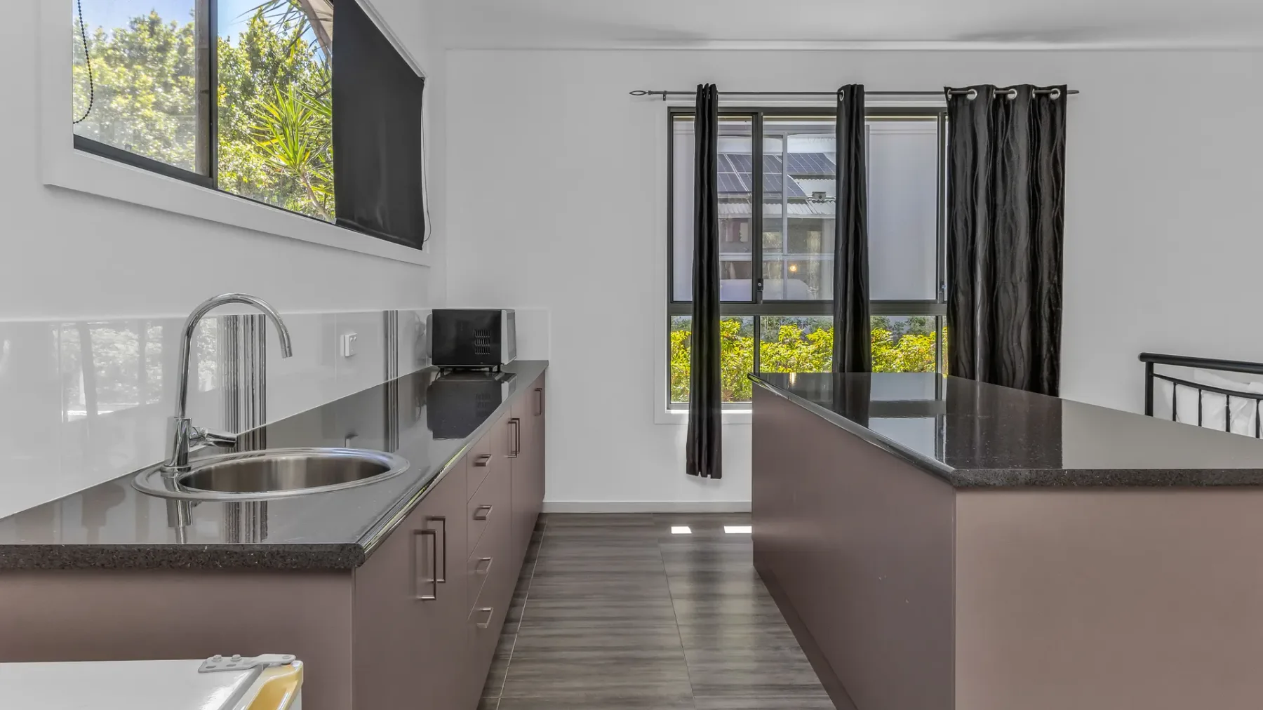 A modern kitchen with dark counters, cabinetry, and a central island.
