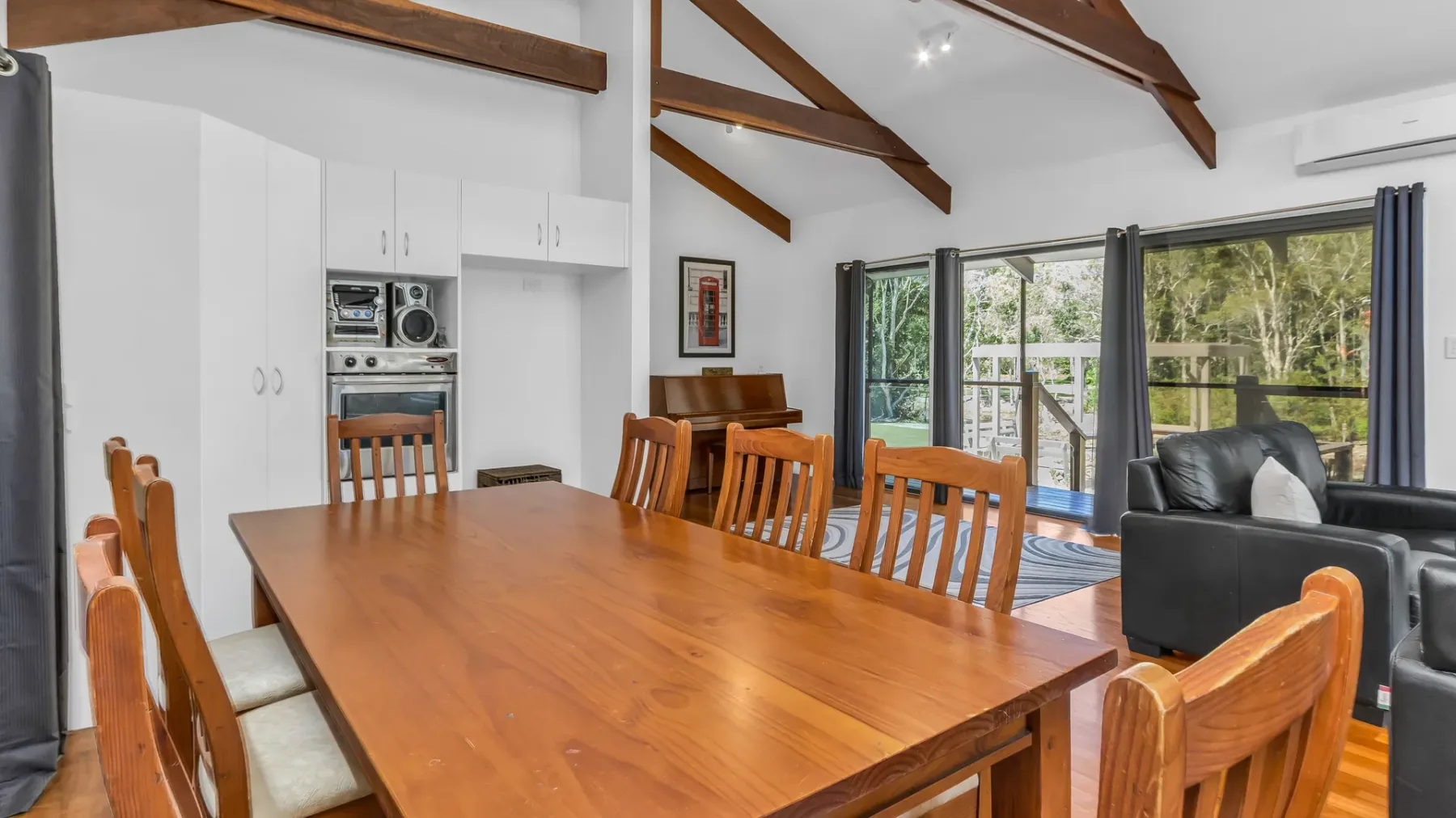 A dining area with a long wooden table beside a living area and glass doors.