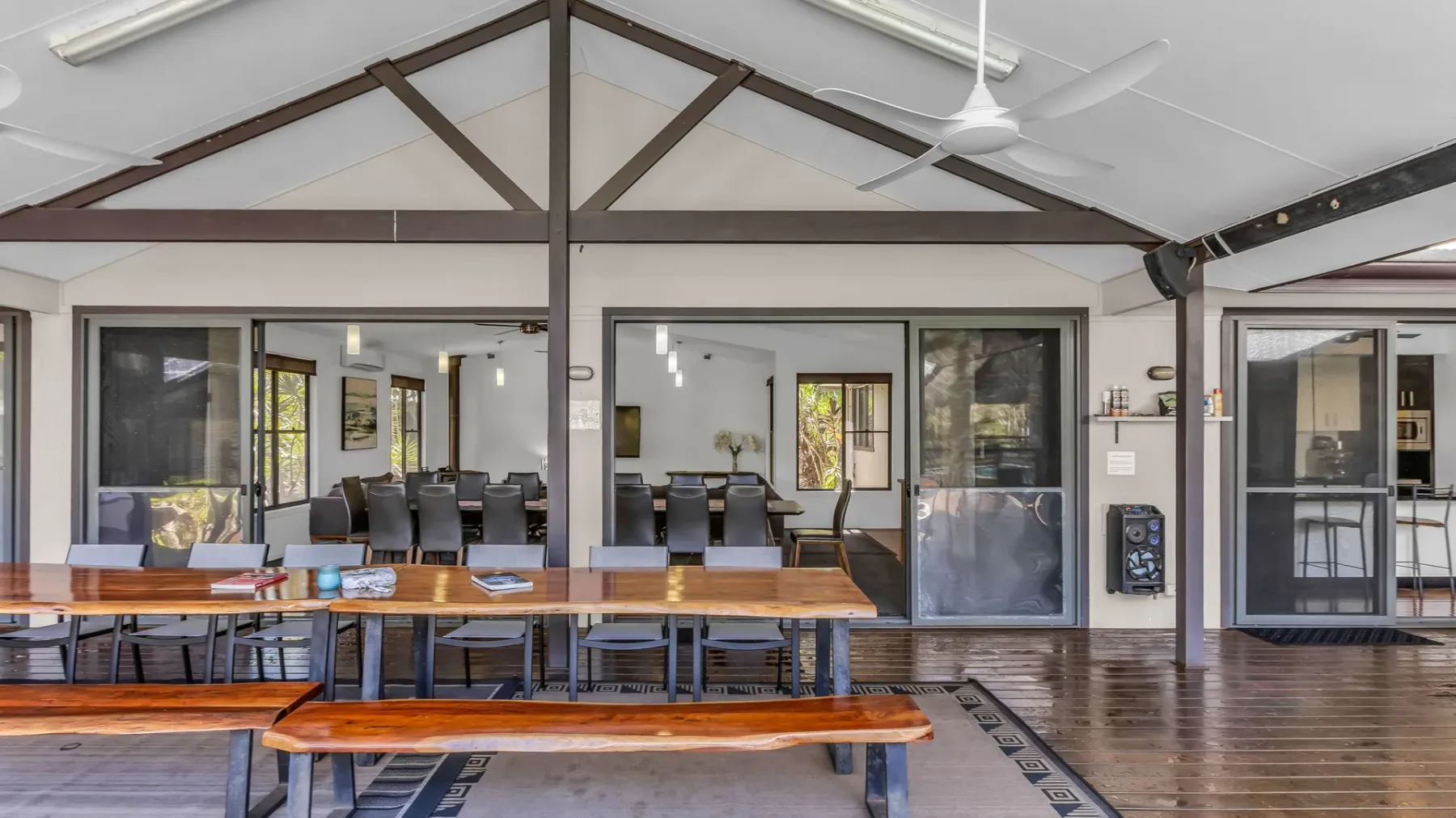 A spacious dining area with long wooden tables beneath exposed roof beams.