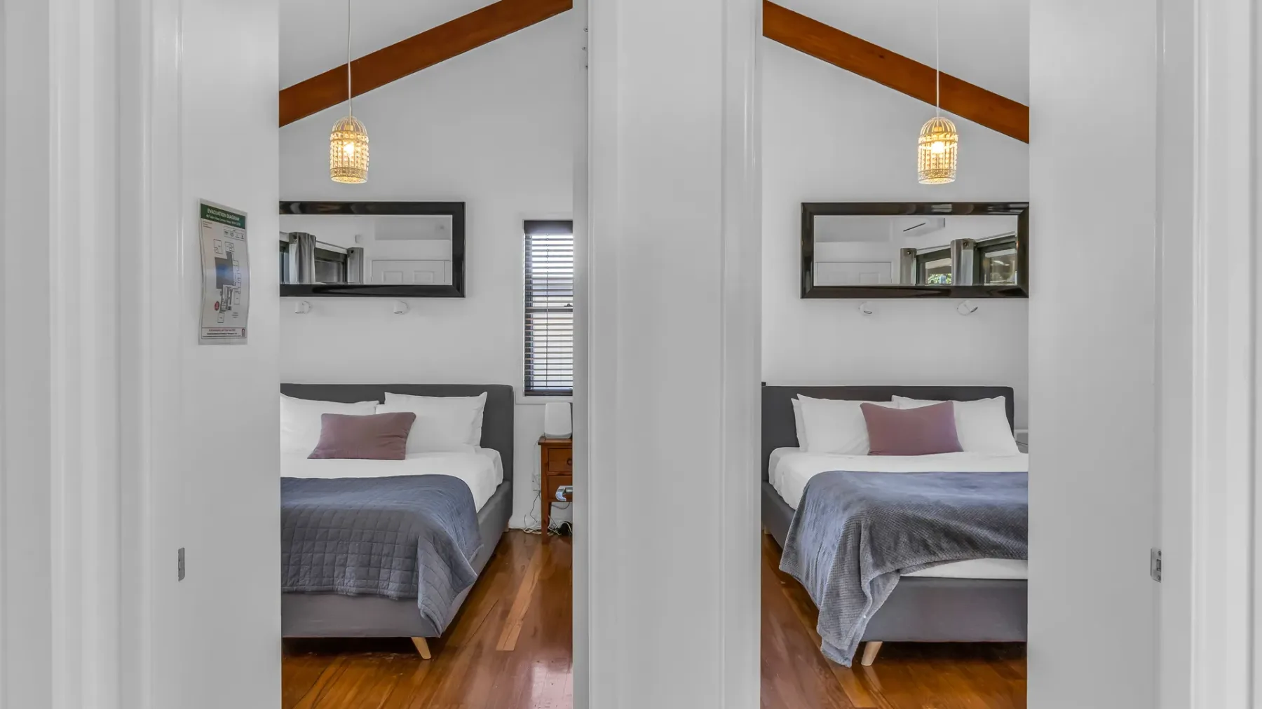 A bedroom with a bed beneath a sloped ceiling and a hanging light.
