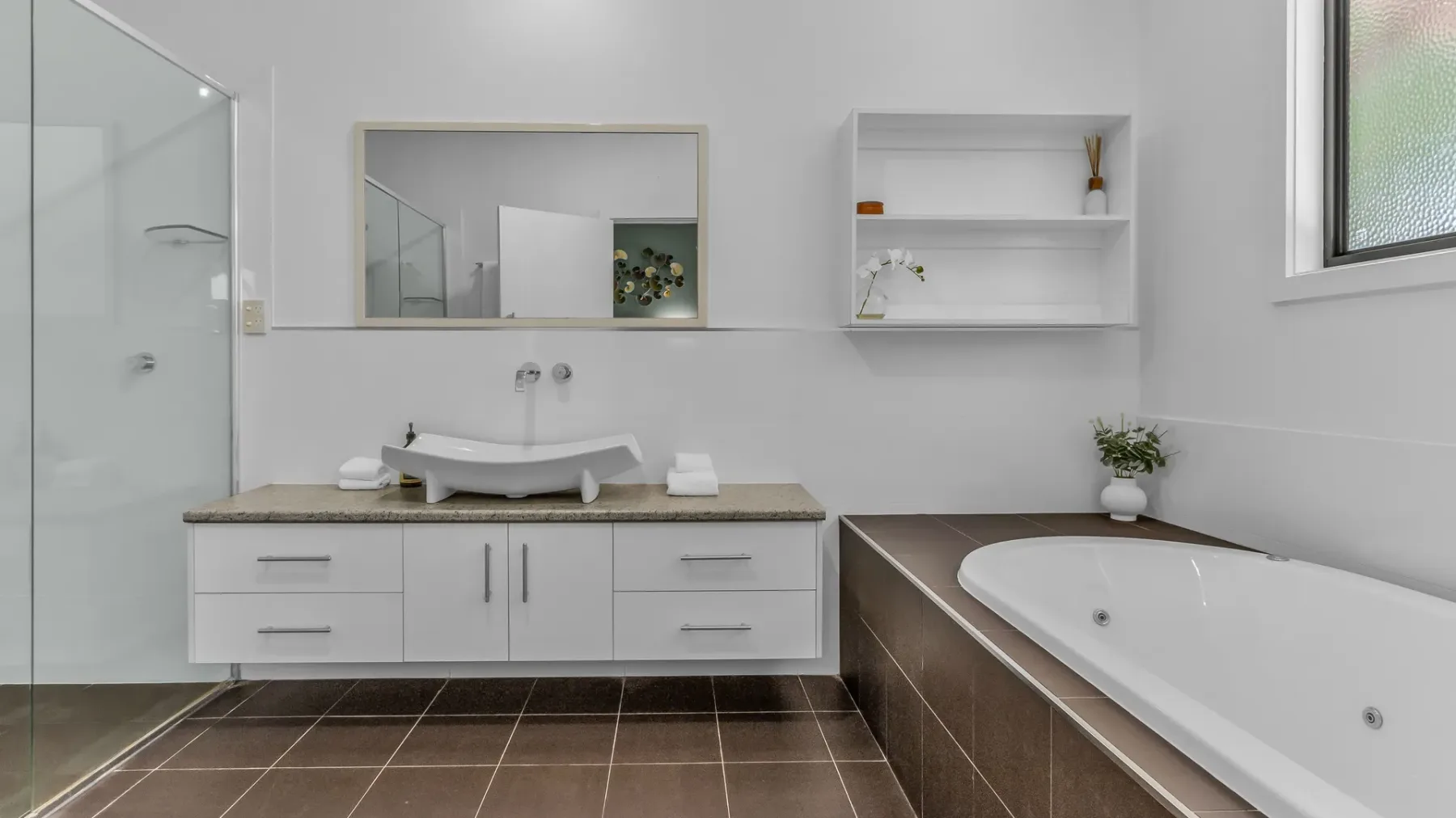 A bright bathroom with a bathtub, vanity, and wall mirror.