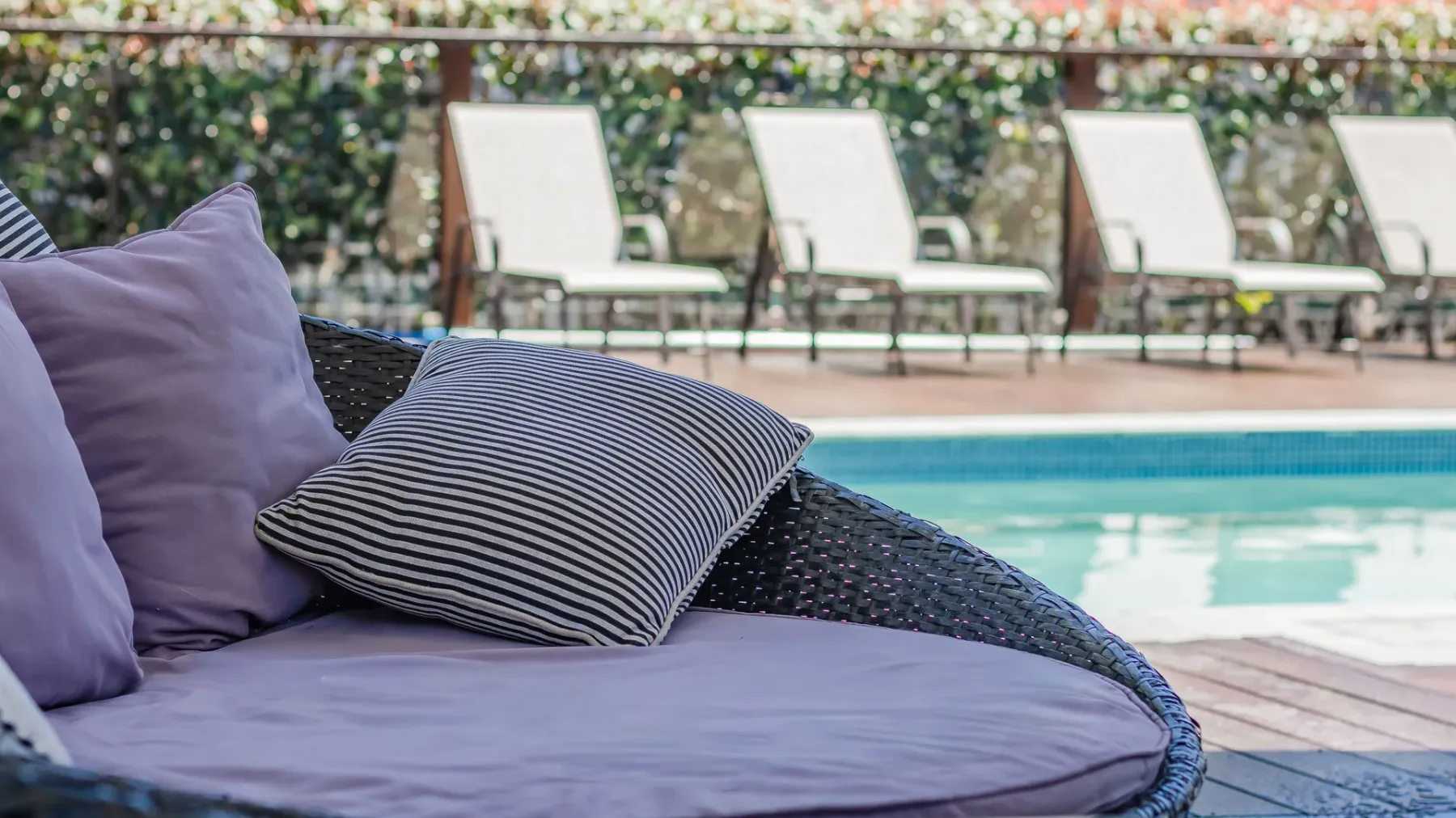 A poolside seating area with cushions beside a swimming pool.