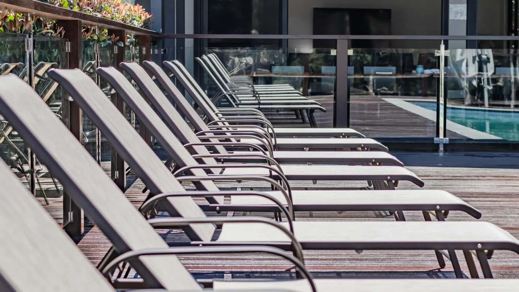 A row of lounge seating lines the edge of an outdoor pool.