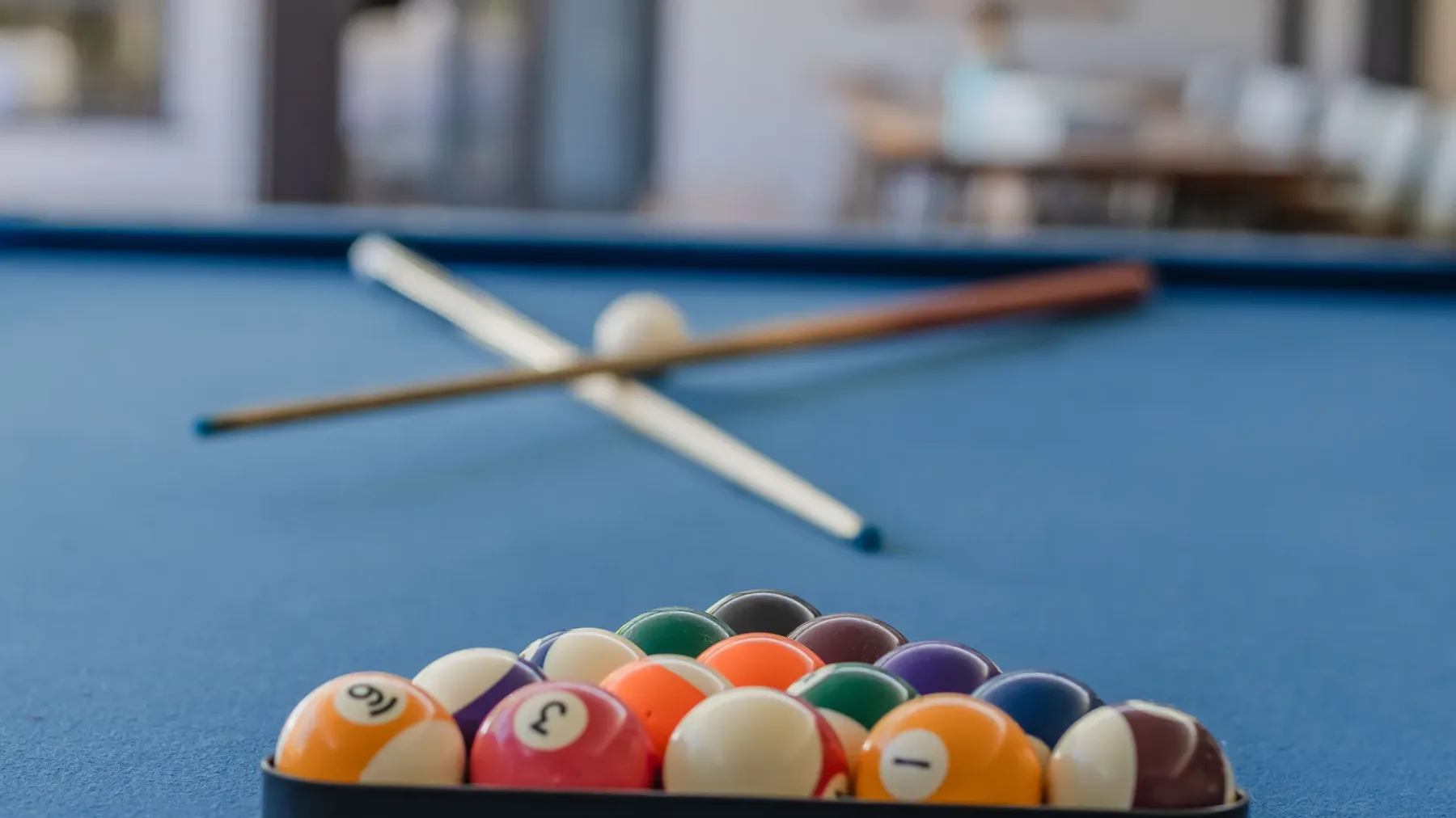 A pool table with a cluster of billiard balls and crossed cues.