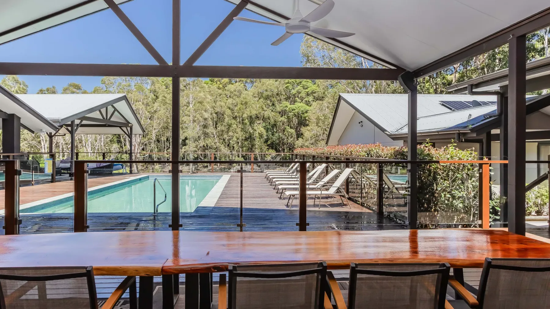 A covered outdoor dining area overlooks a pool and rows of lounge seating.