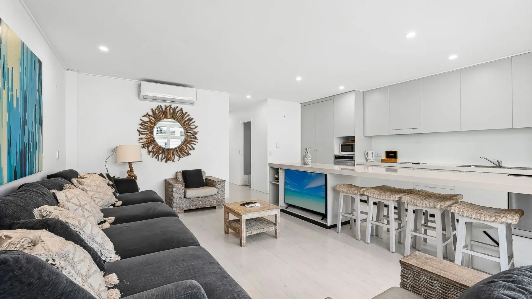 Una sala de estar y cocina de concepto abierto con sofá seccional y asientos en la isla.