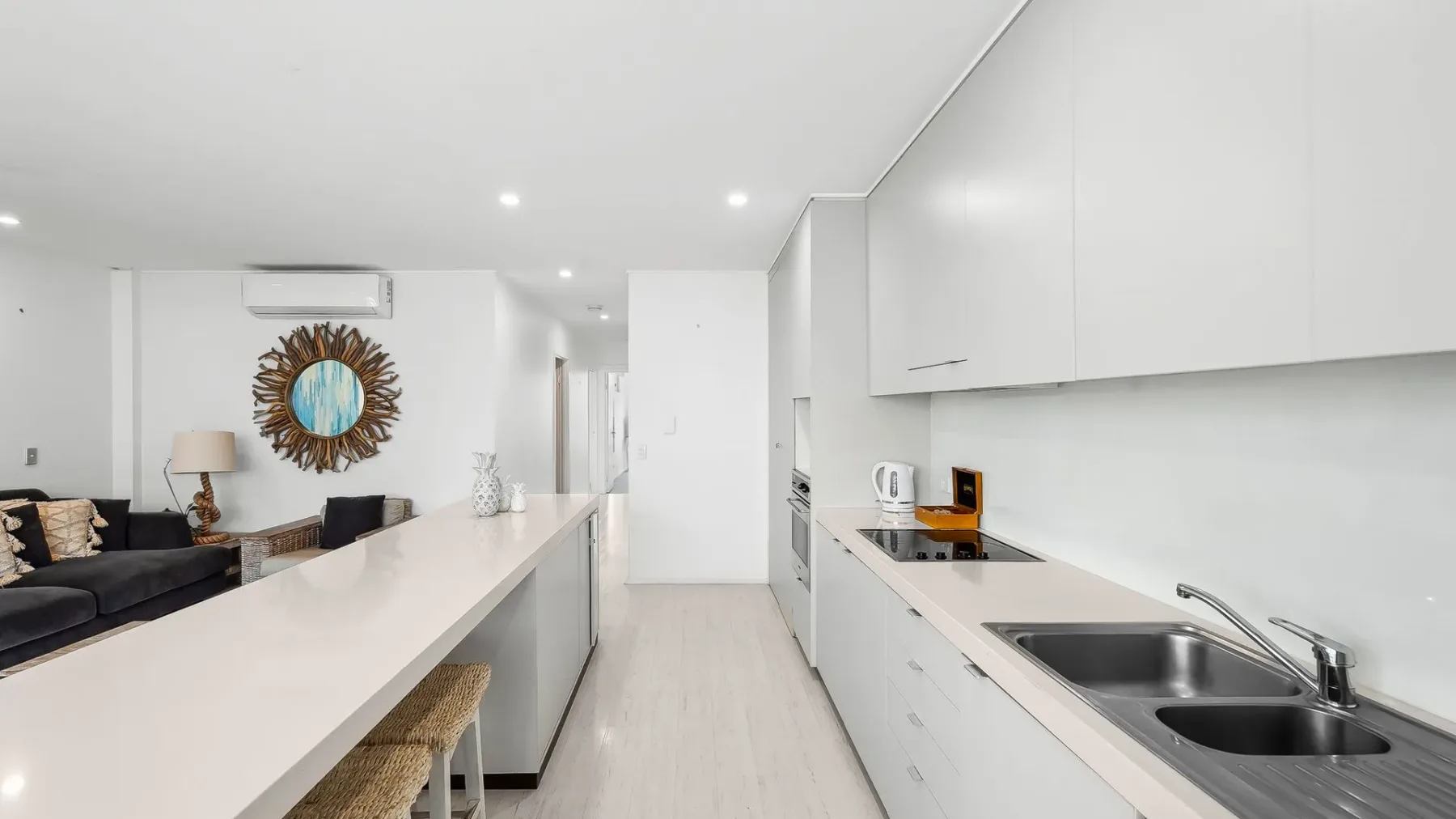 Una cocina luminosa y abierta con una encimera larga y una sala de estar contigua.
