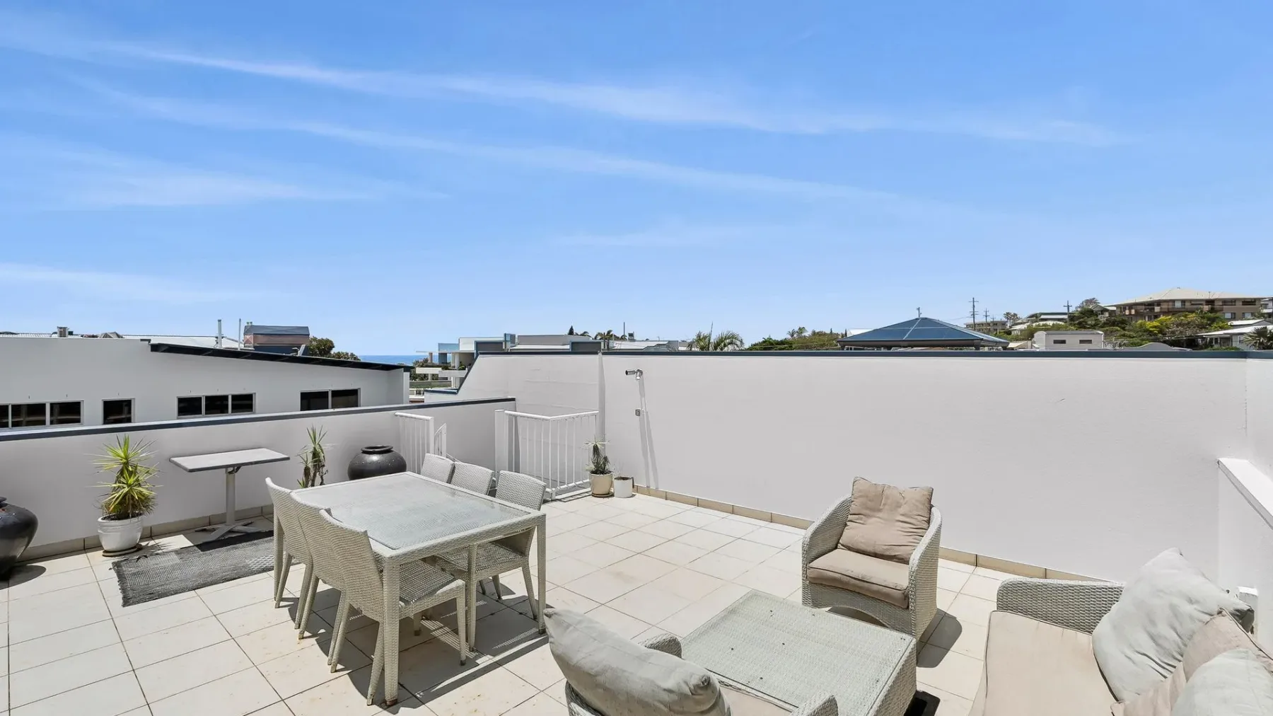 Una terraza soleada en la azotea con comedor y una zona de descanso.
