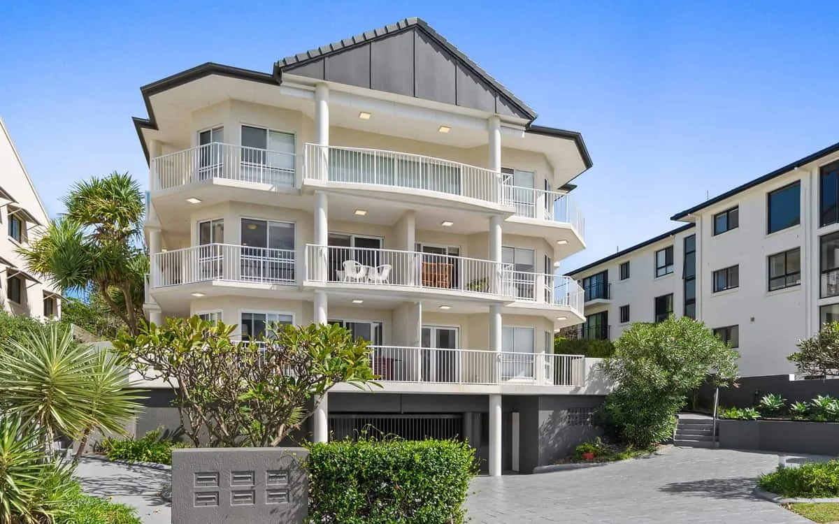 Zona común: Edificio residencial de varias plantas con balcones y jardines.