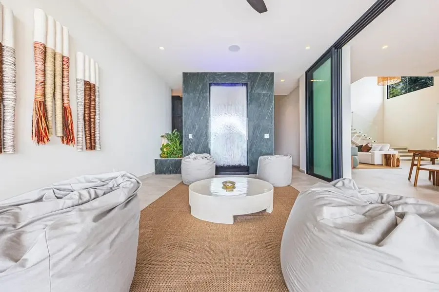 A modern lounge with low seating, a round coffee table, and a stone feature wall.