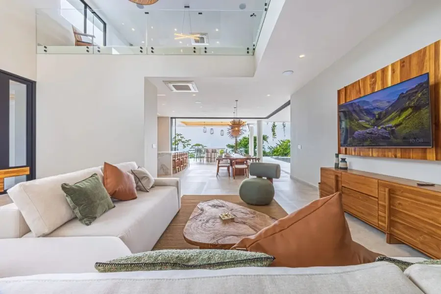 A bright living room with seating, a wooden coffee table, and a television.