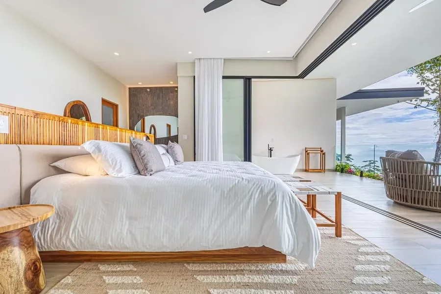 A bright bedroom opens onto a balcony with ocean views.
