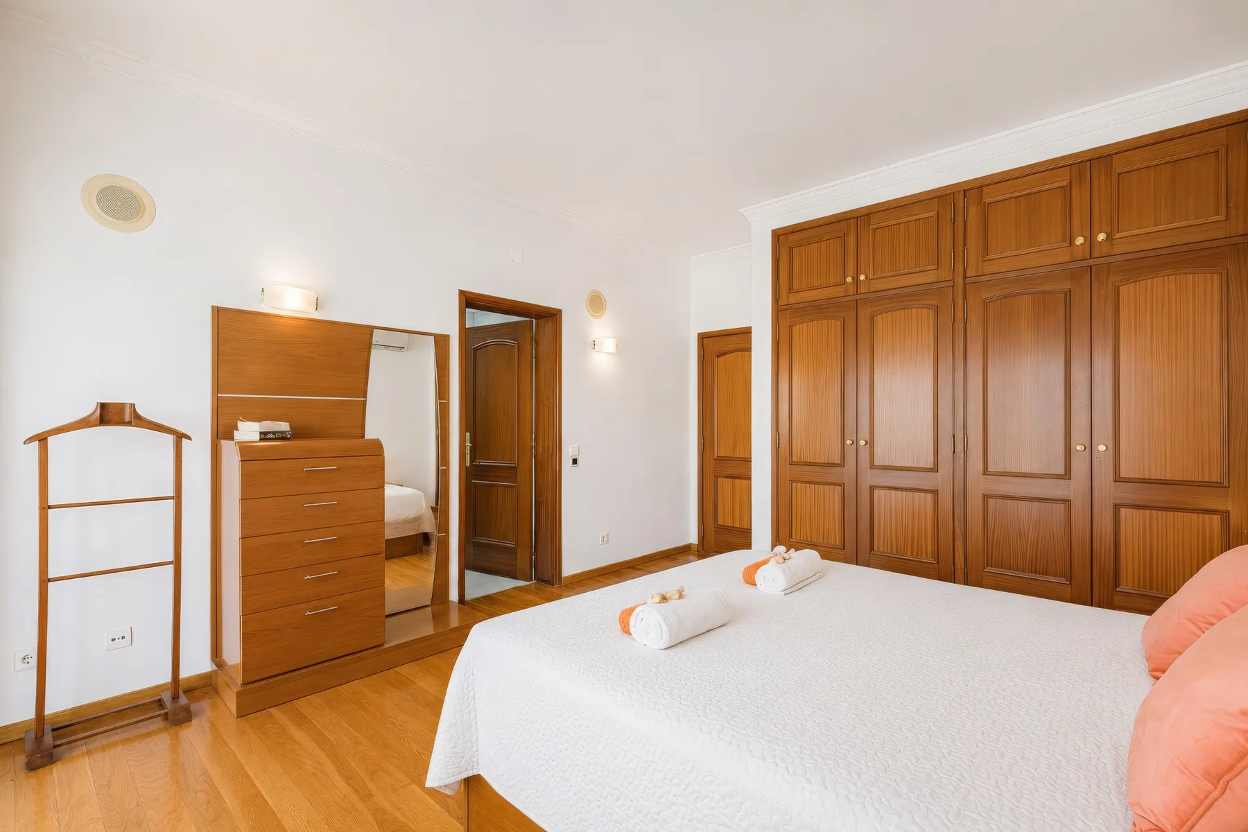 Un dormitorio con una cama bien tendida y armarios de madera.