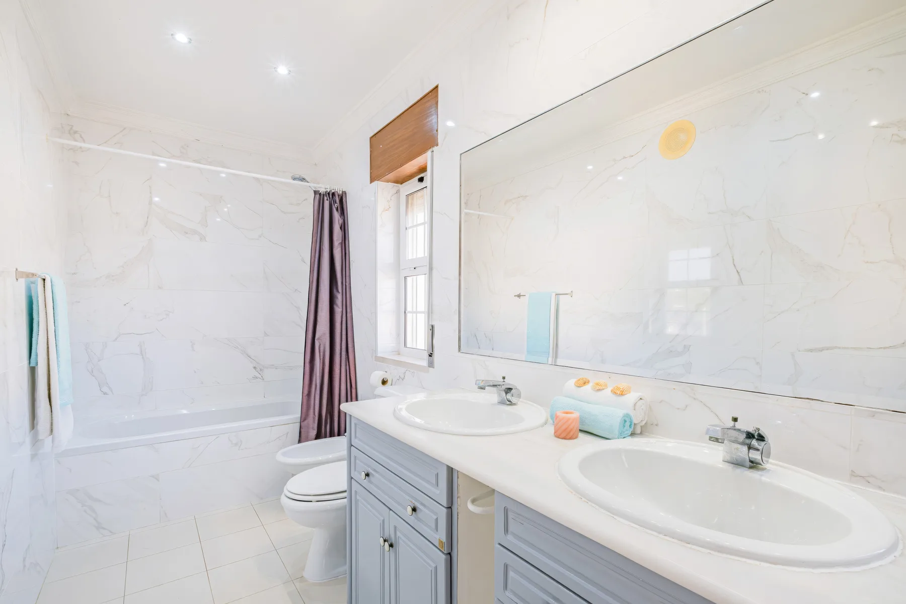 Un baño luminoso con lavabo doble, espejo grande y bañera.