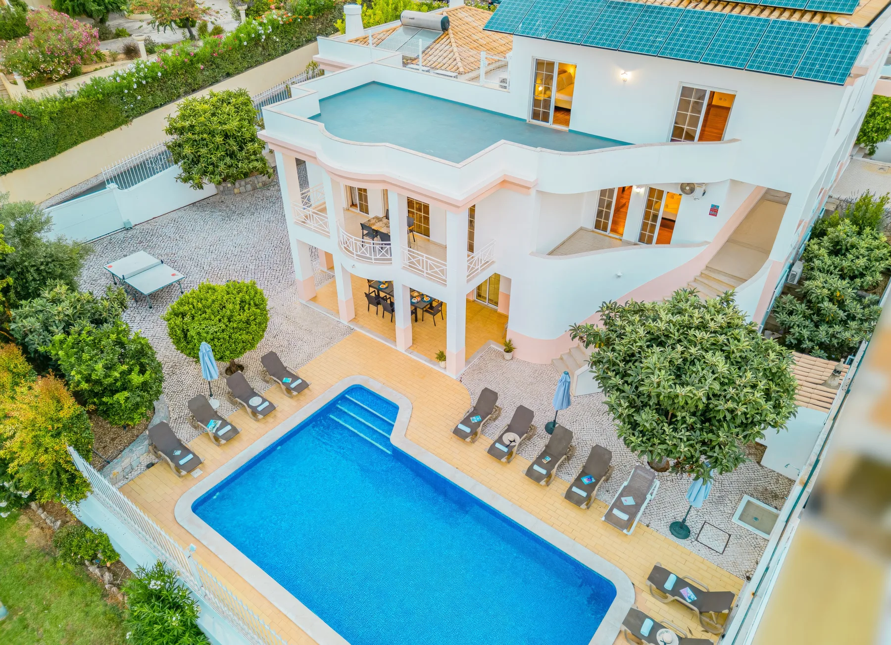 Una vista aérea muestra una casa grande junto a una piscina y asientos en el patio.