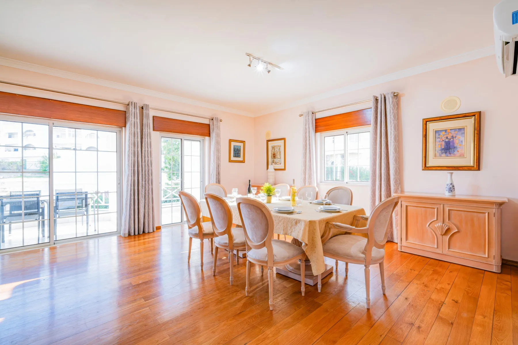 Un comedor luminoso con una mesa puesta junto a grandes ventanas y puertas de vidrio.