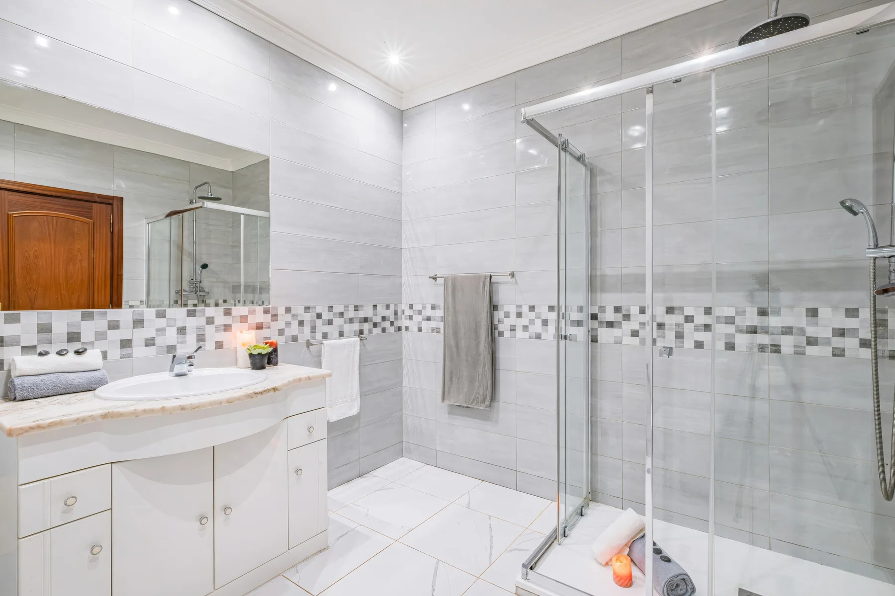 Un baño con azulejos, lavabo y ducha de vidrio.