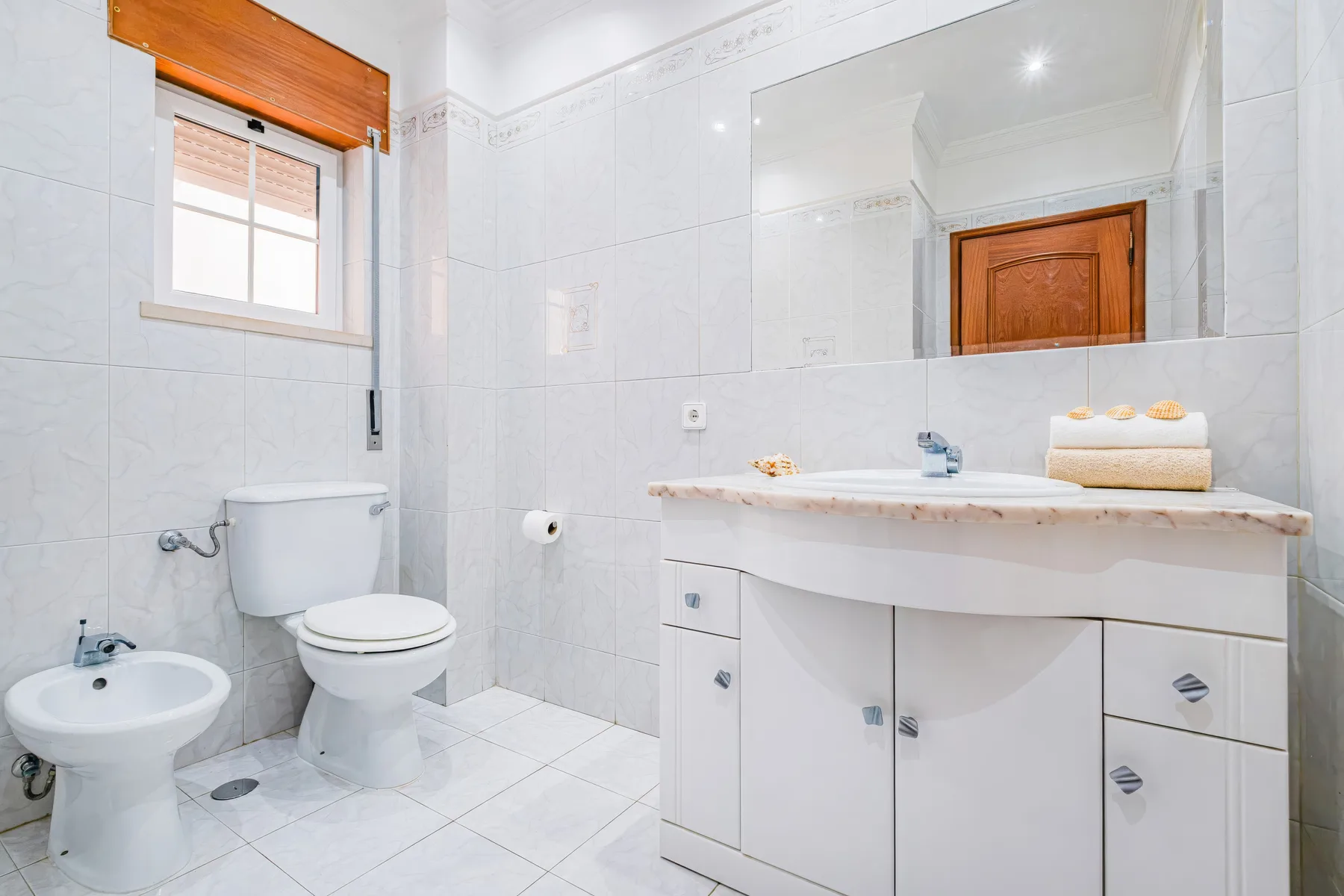 Un baño alicatado con lavabo, inodoro y tocador con espejo.