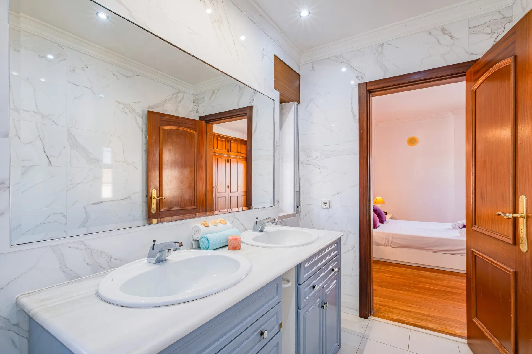 Un baño luminoso con un tocador largo, dos lavabos y un espejo grande.