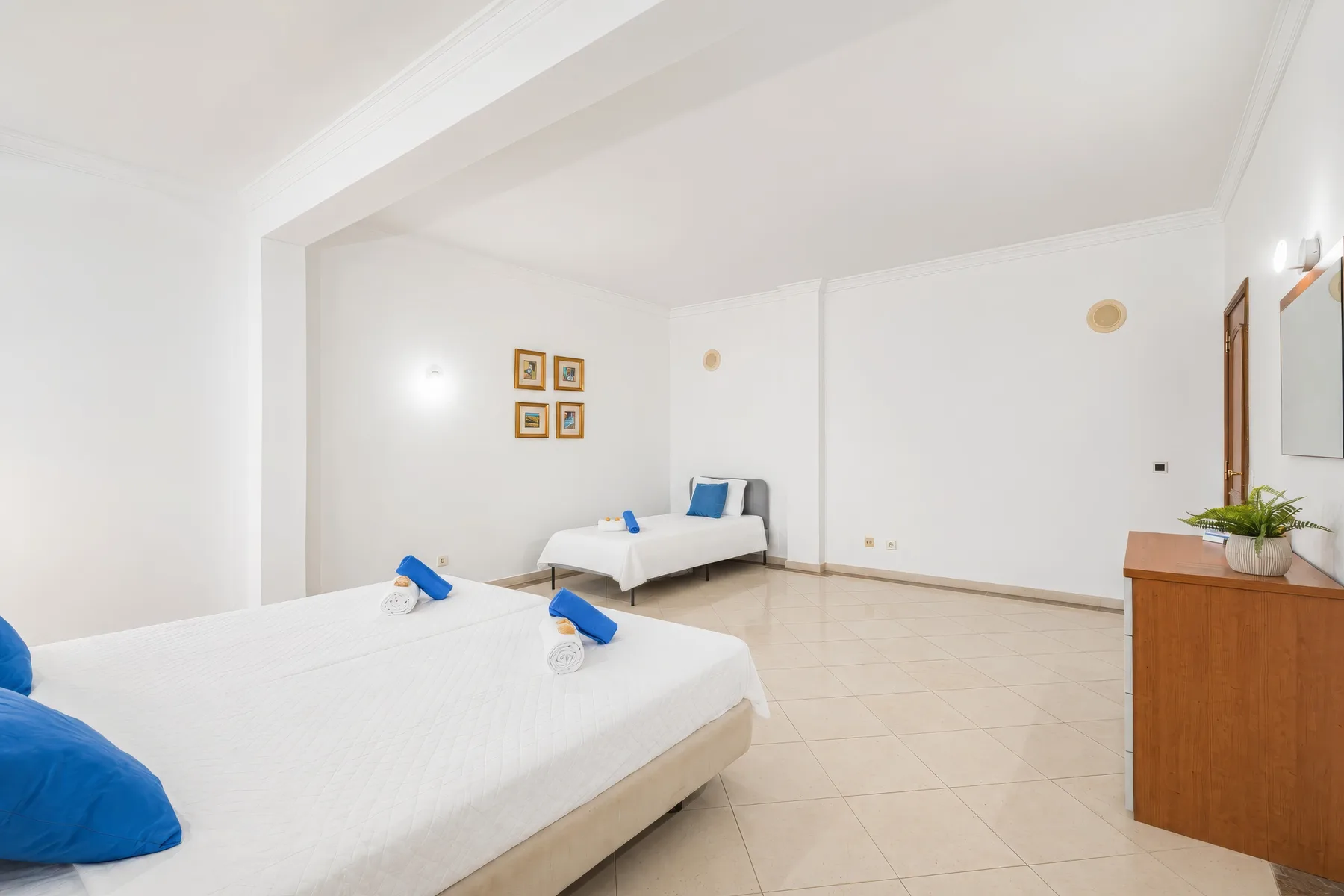 Un dormitorio luminoso con dos camas y una cómoda de madera.