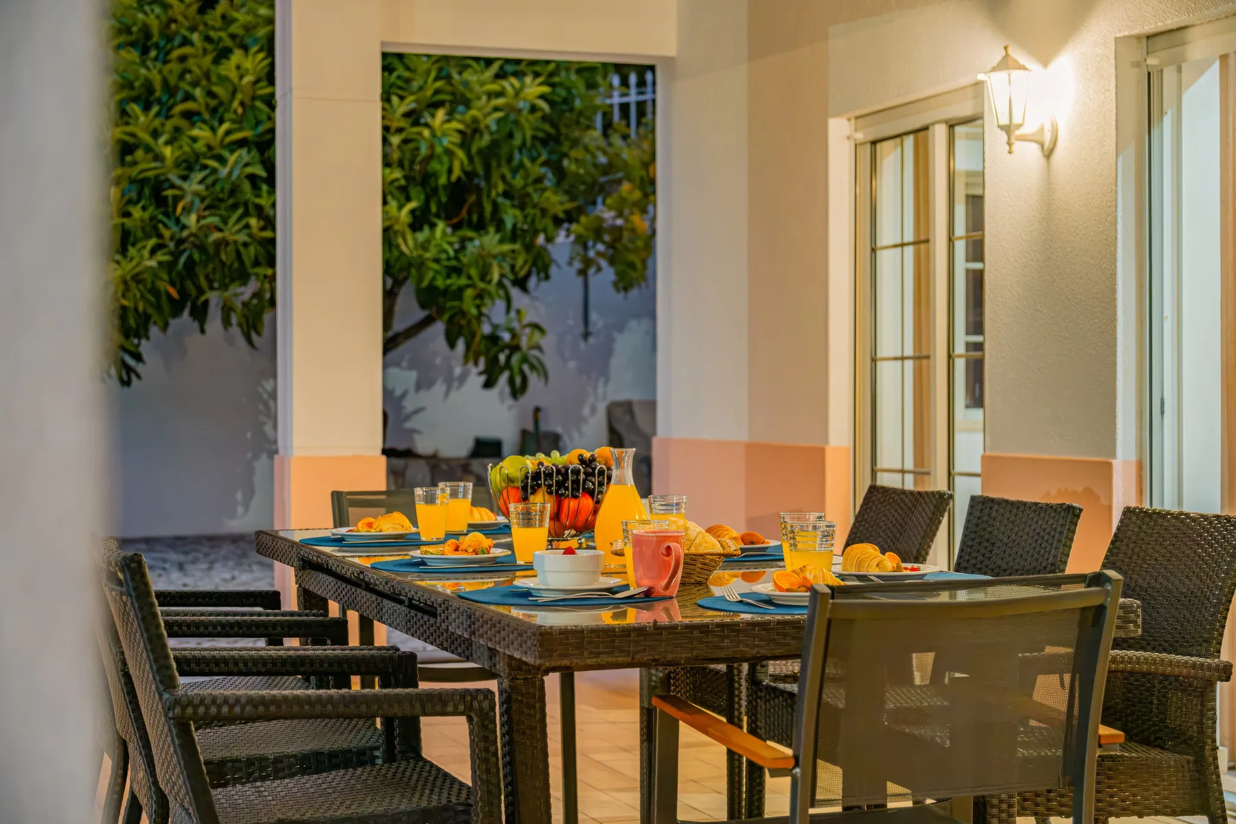 Un comedor en un patio cubierto con la mesa preparada para comer.
