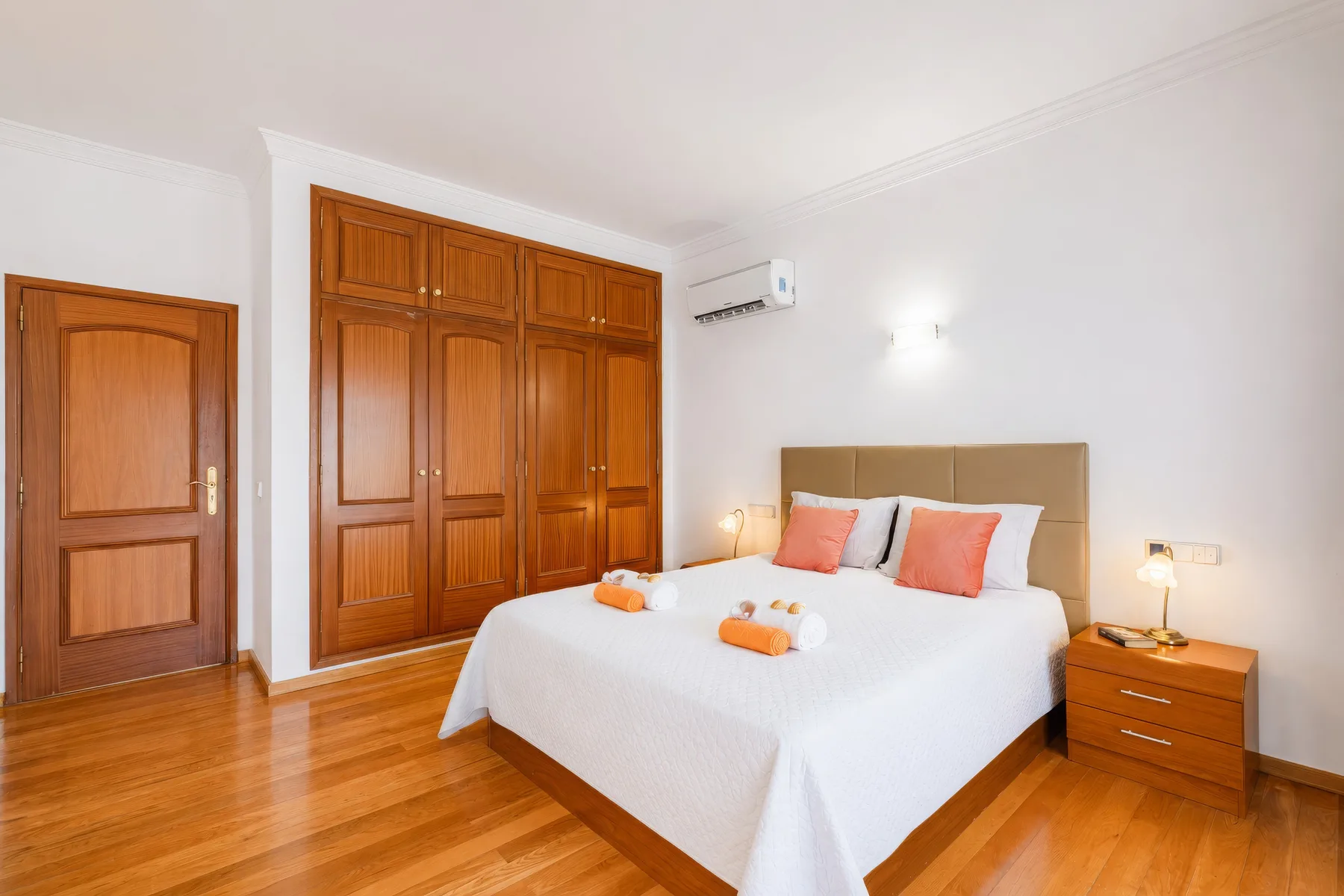 Un dormitorio con una cama doble, armarios de madera y una mesita a juego.