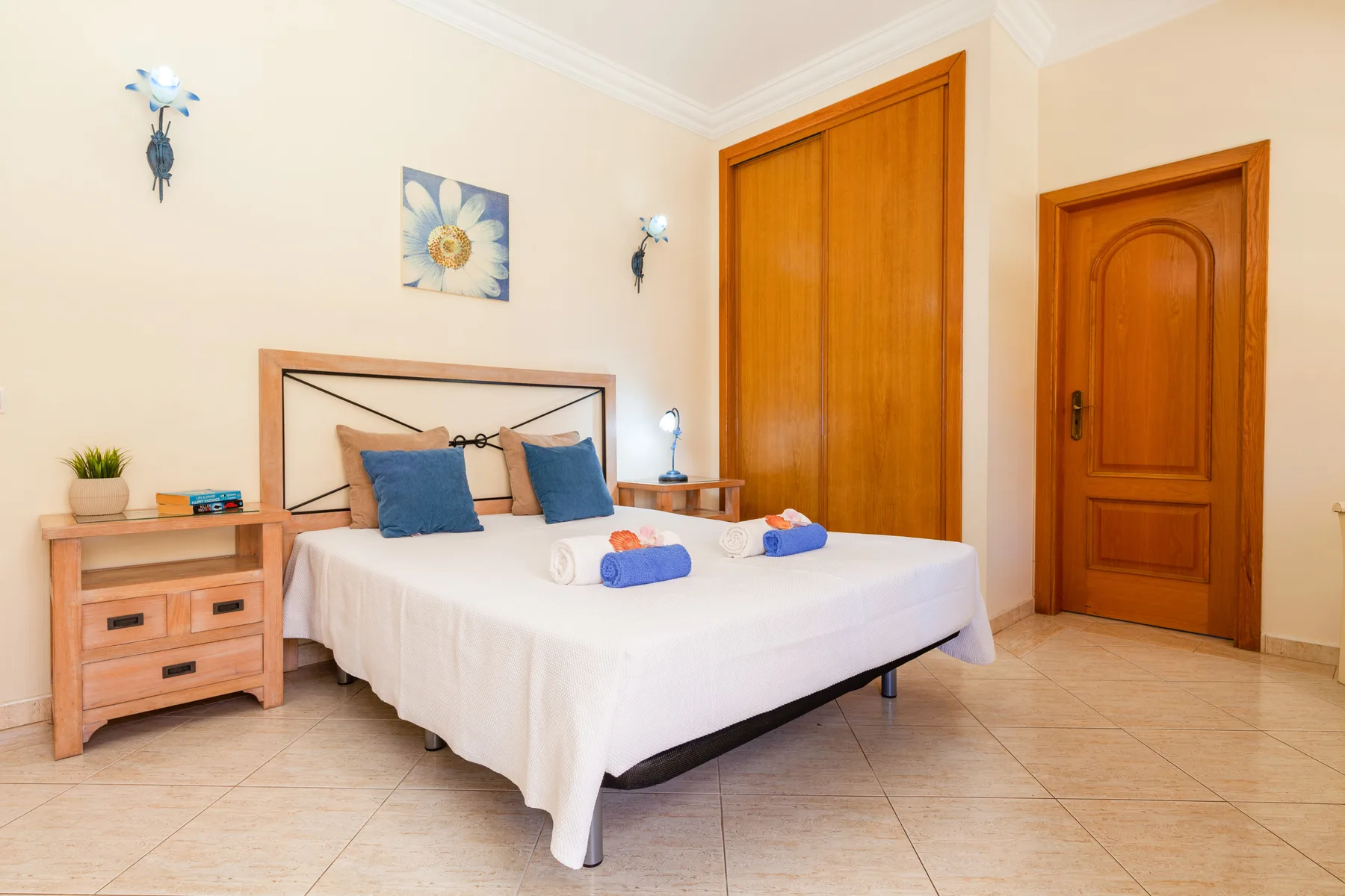 Un dormitorio con una cama doble, puertas de madera y suelo de baldosas claras.