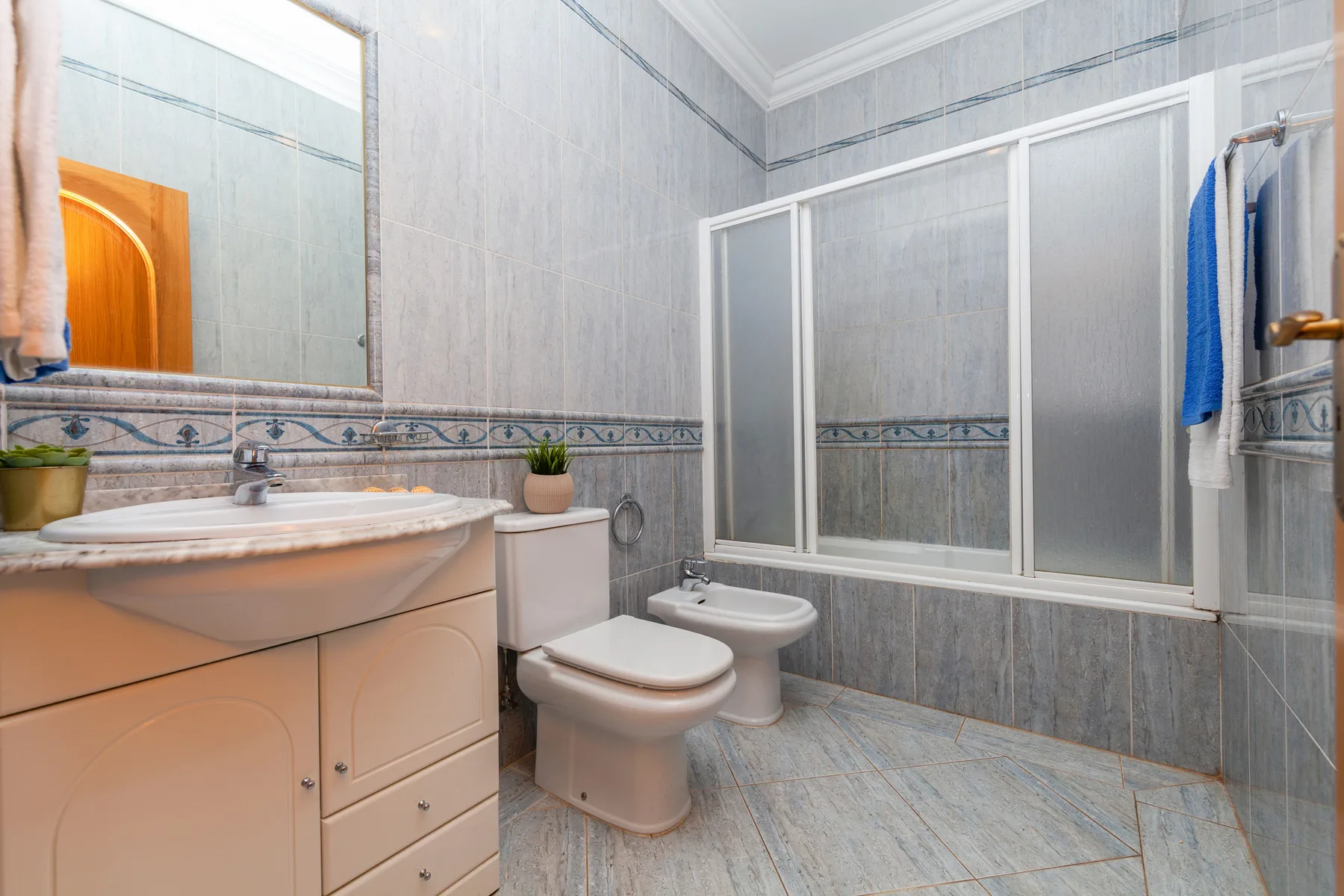 Un baño con azulejos, lavabo, inodoro, bidé y cabina de ducha.