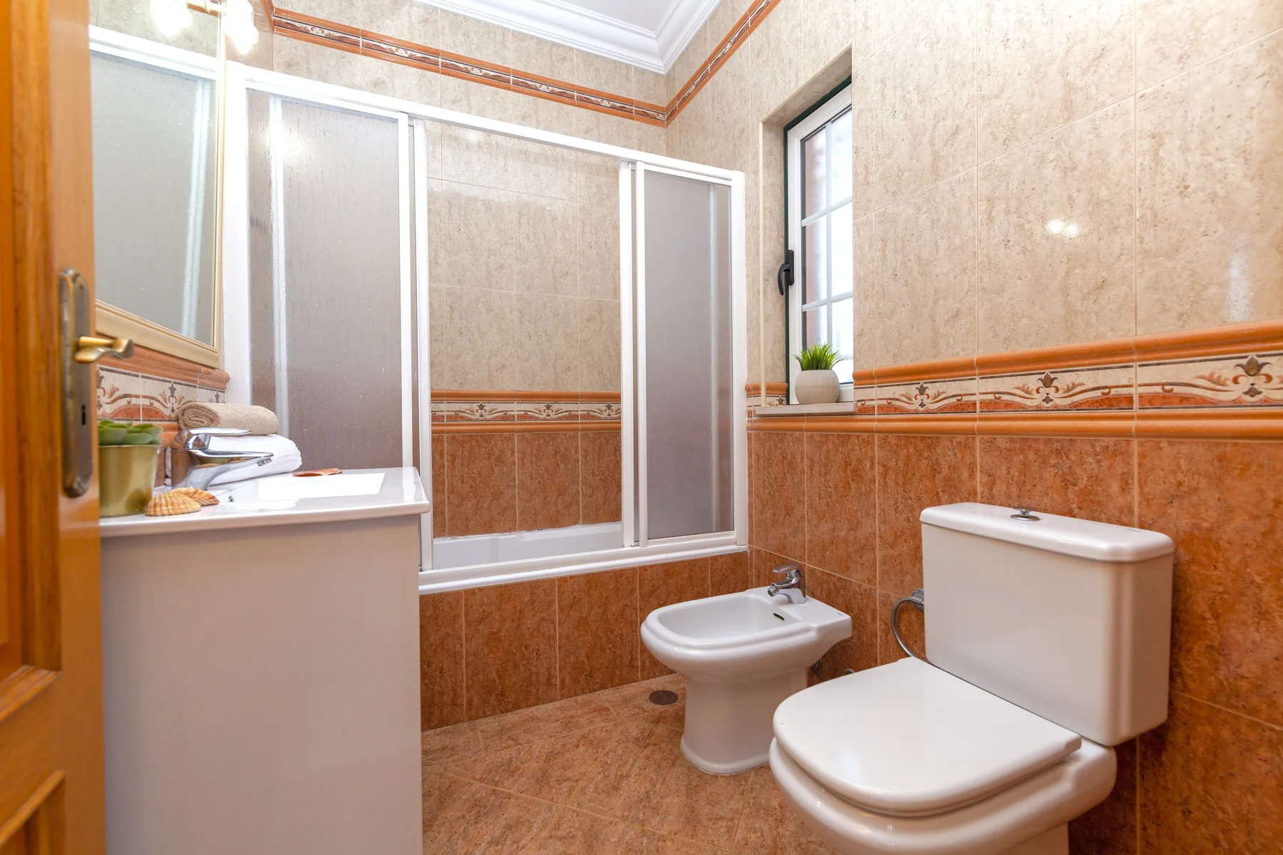 Un baño con ducha, lavabo, bidé e inodoro.