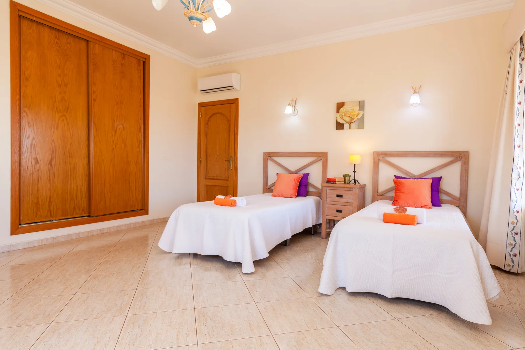 Un dormitorio con dos camas individuales, mesitas de noche y un gran armario de madera.