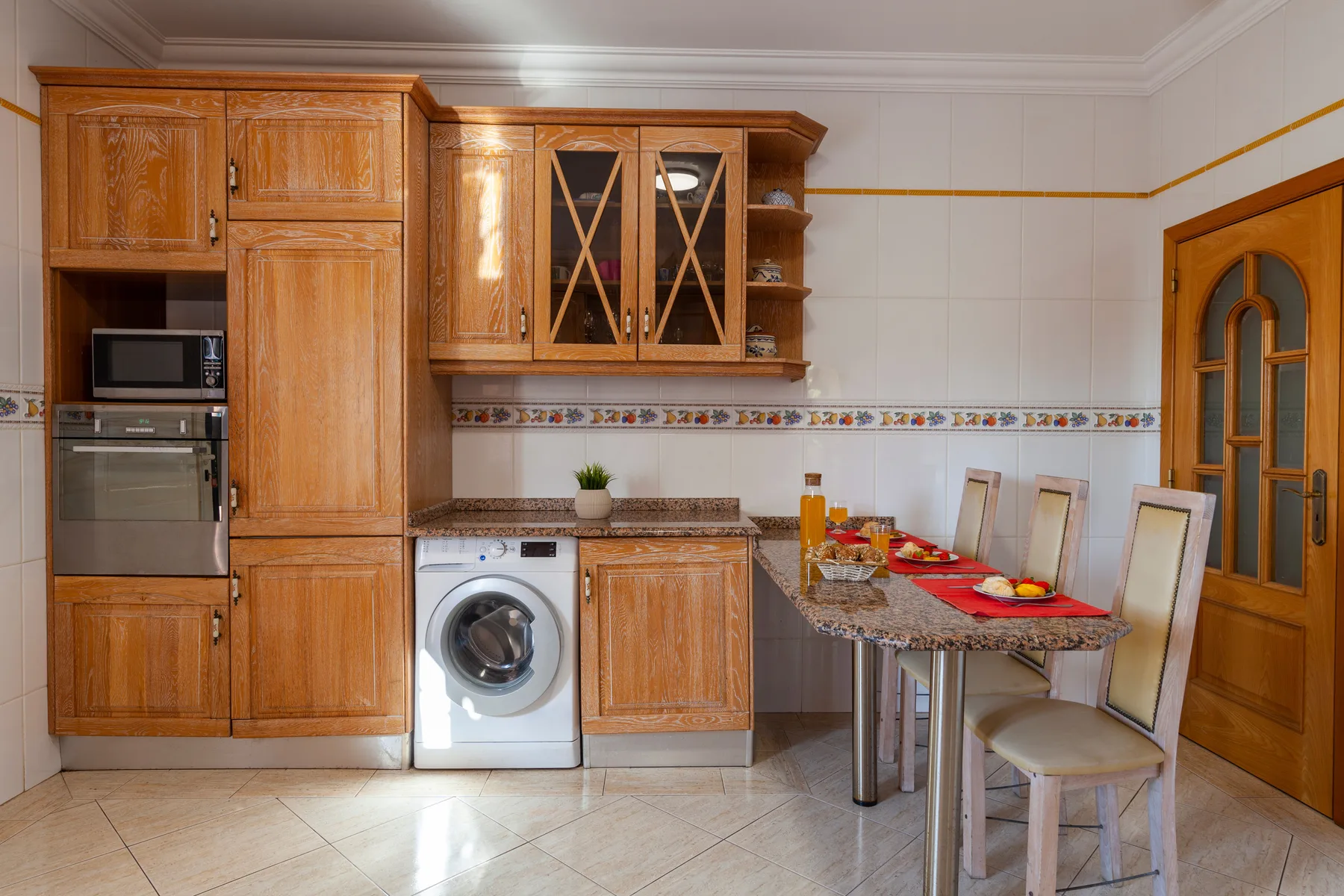 Una cocina con armarios de madera, electrodomésticos y una mesa de comedor.