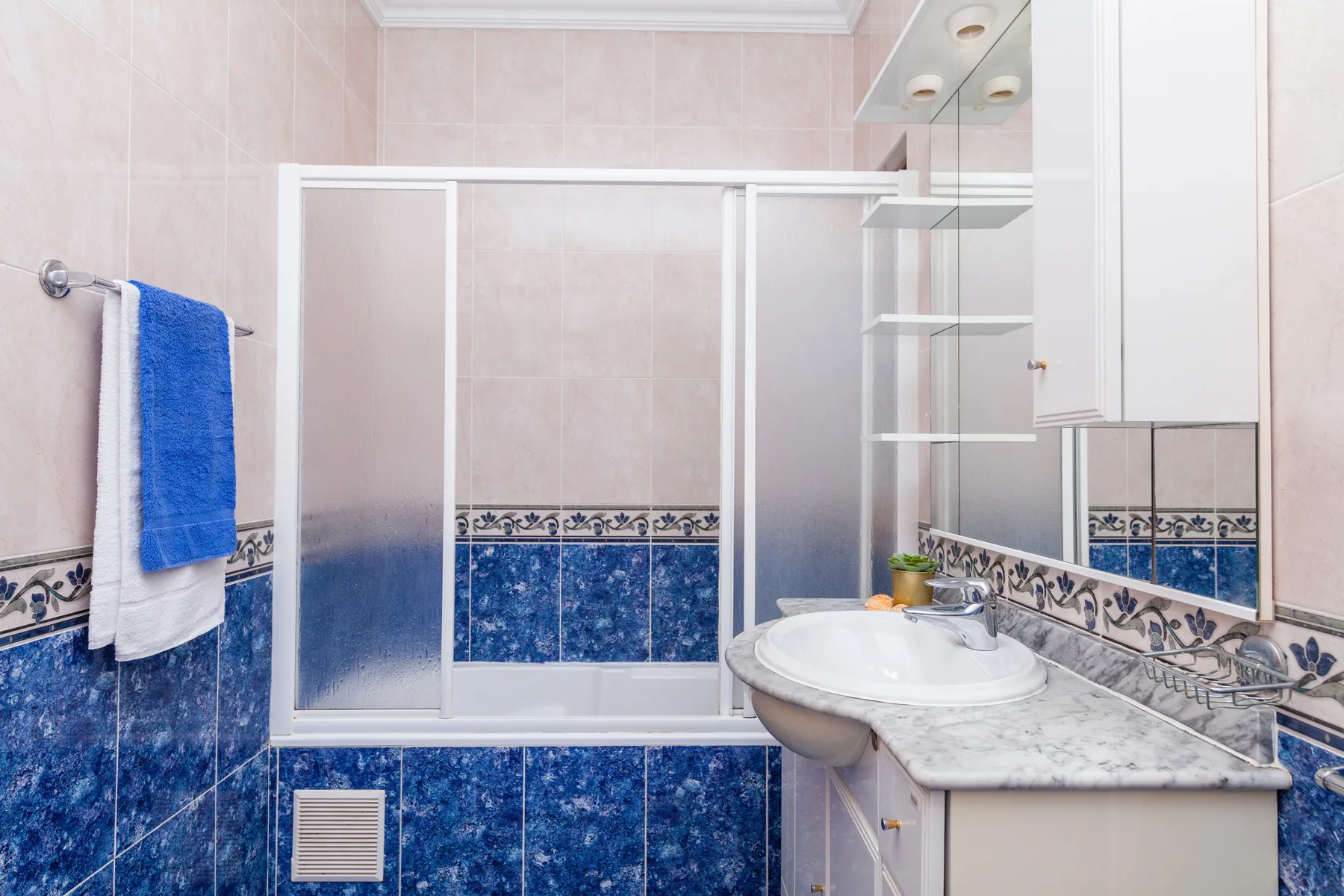 Un baño alicatado con bañera, lavabo y tocador con espejo.