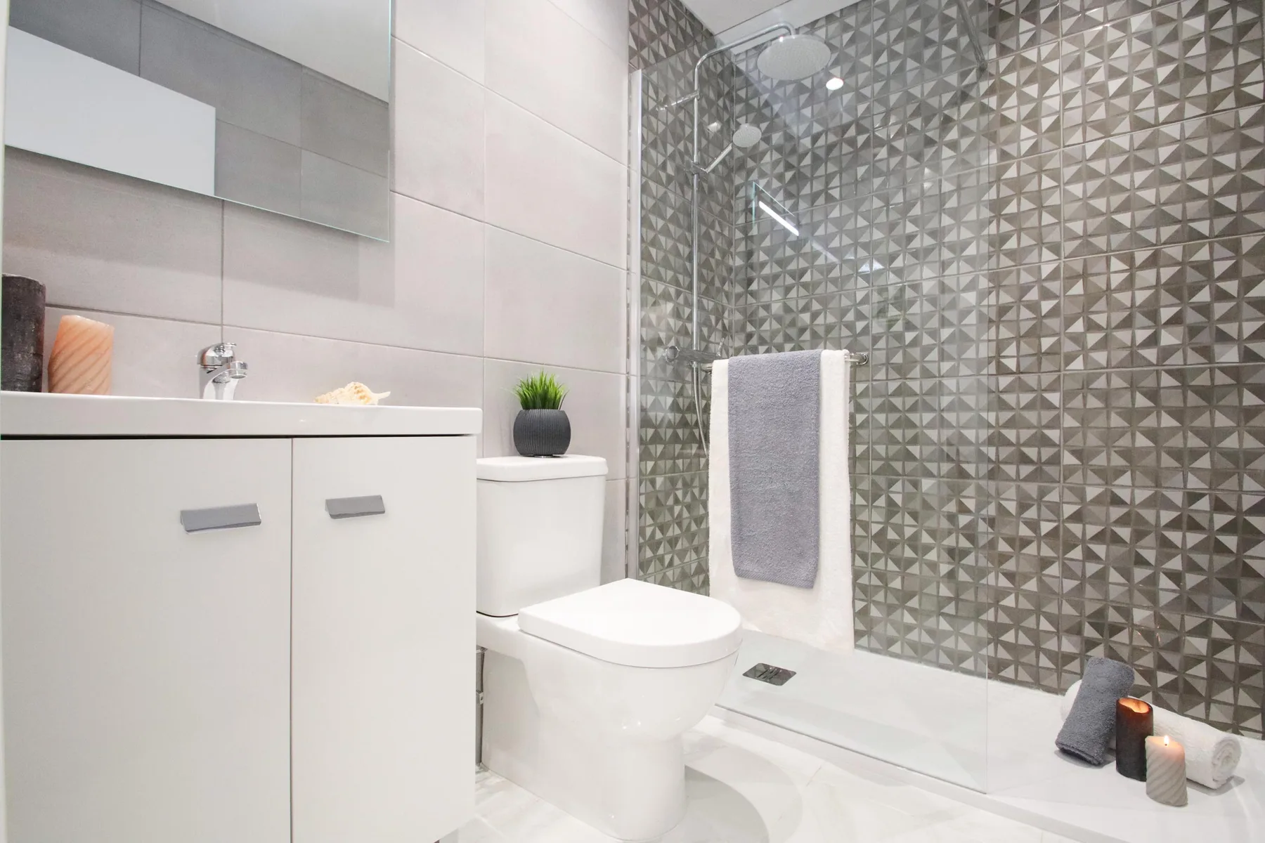 Un baño moderno con un tocador blanco y una ducha con mampara de vidrio.