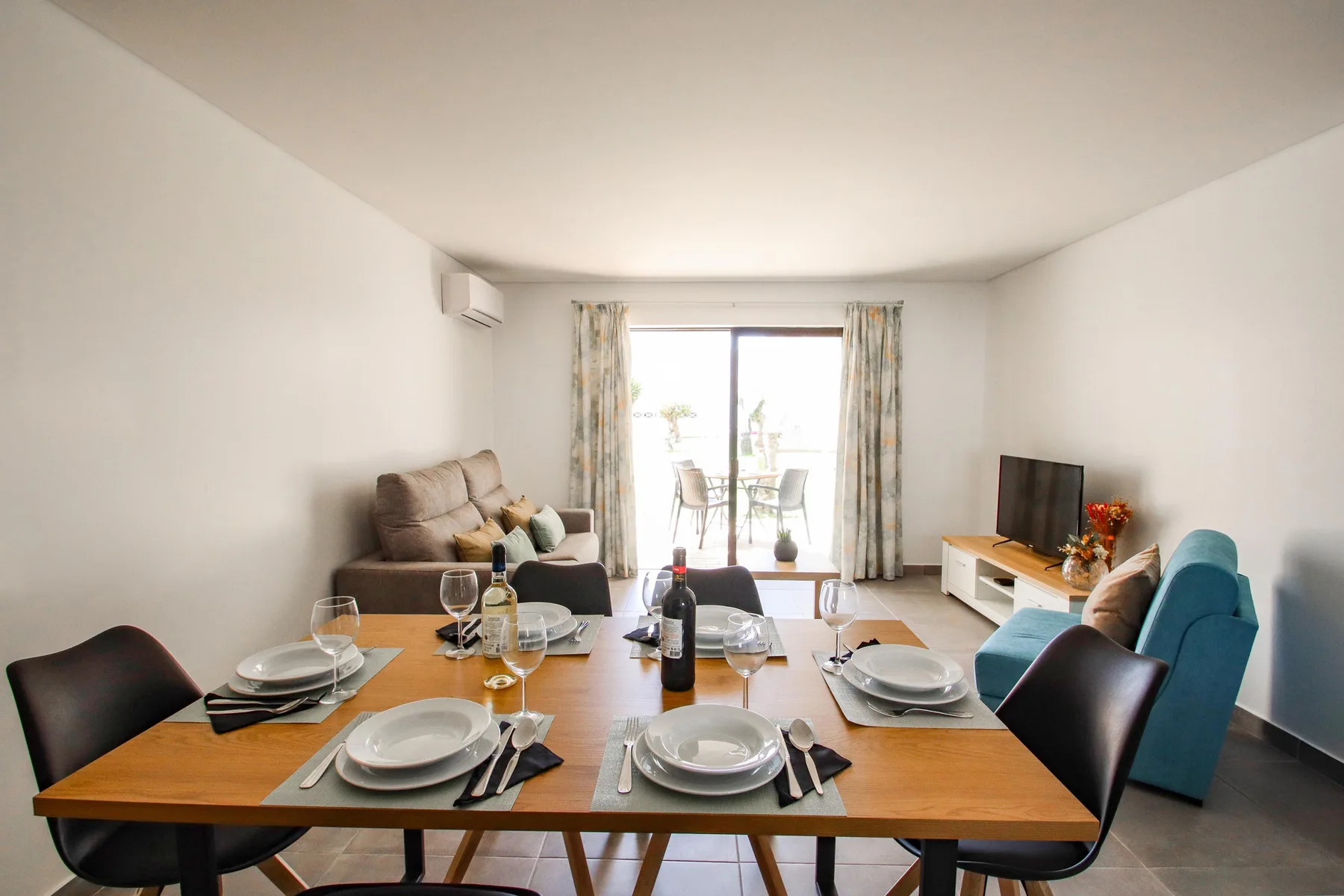 Una luminosa sala de estar y comedor, con una mesa puesta frente a una zona de asientos.