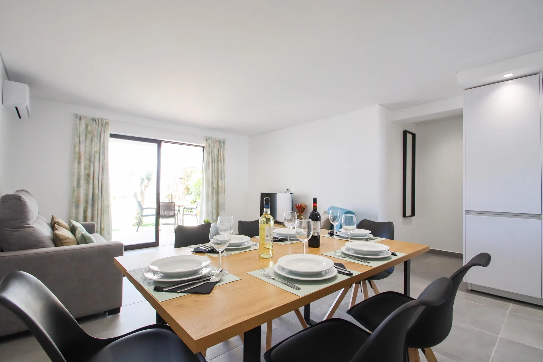 Comedor con la mesa puesta junto a una ventana luminosa.