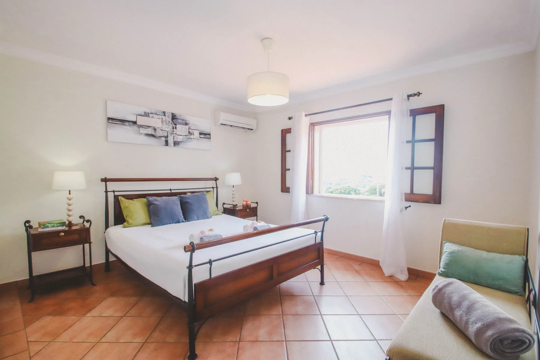 Un dormitorio con cama doble, mesas de noche y una ventana grande.