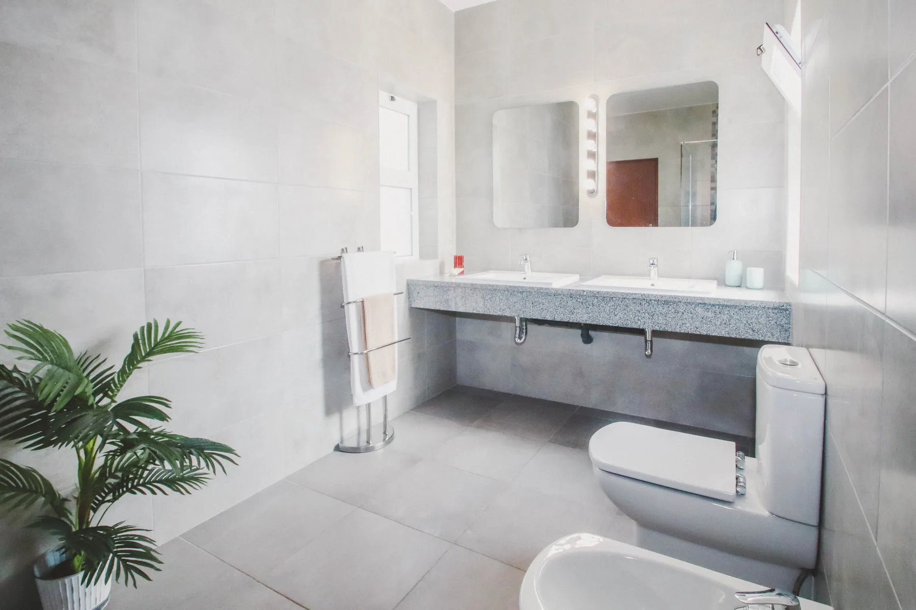Un baño luminoso con una encimera larga, un espejo y un inodoro.