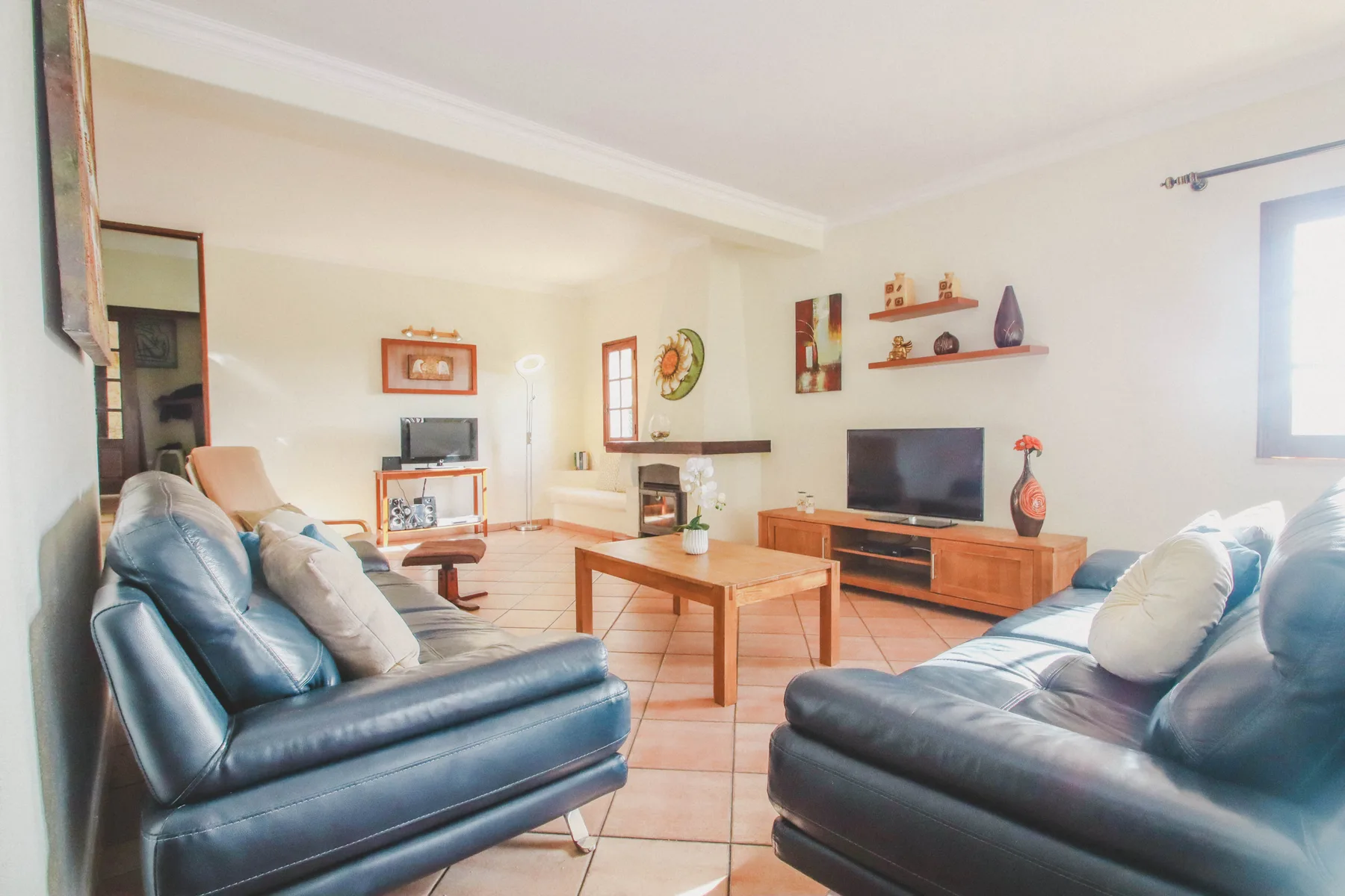 Una sala de estar luminosa con dos zonas de asientos, una mesa de centro y un televisor.