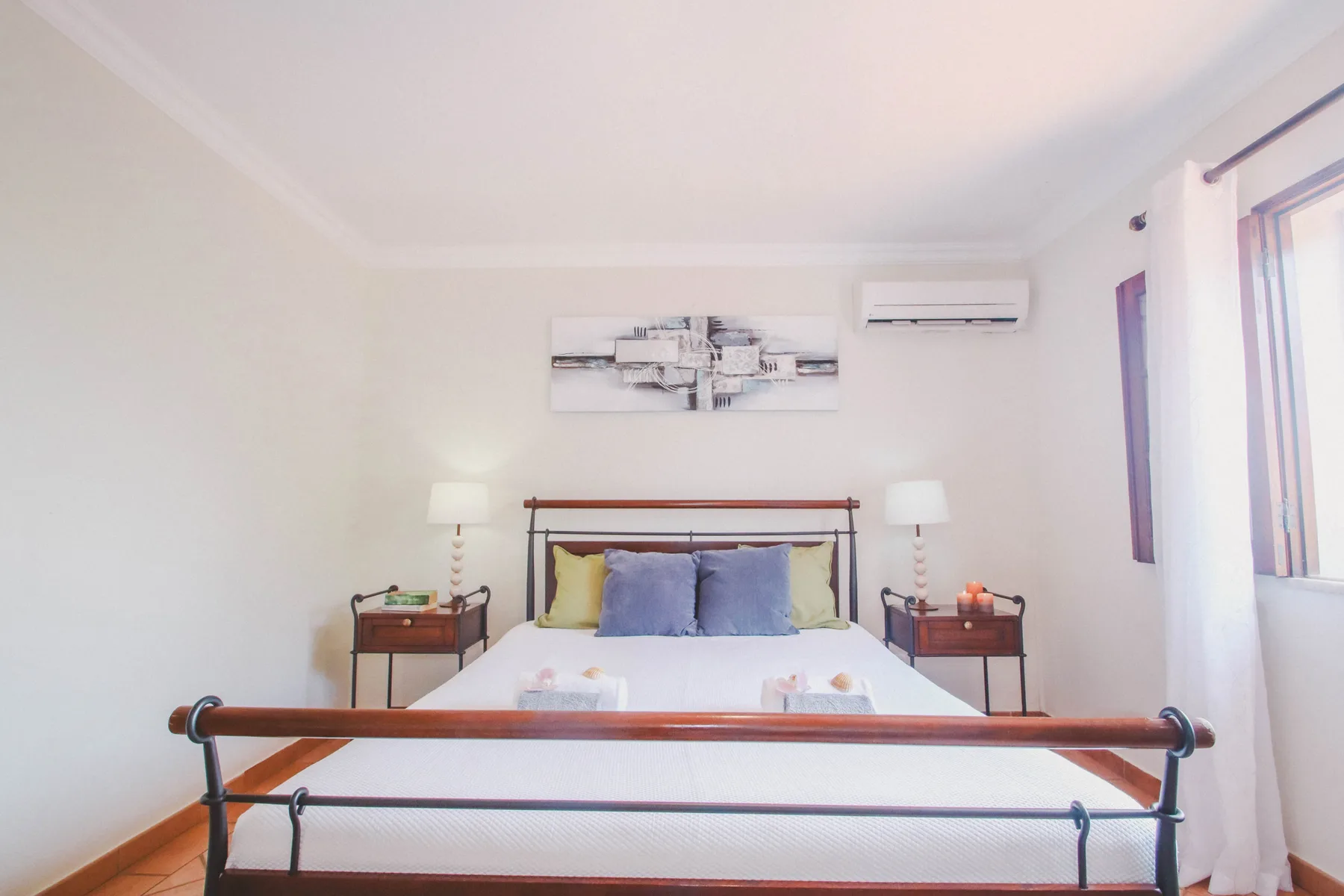 Un dormitorio luminoso con una cama bien tendida y mesitas de noche a juego.