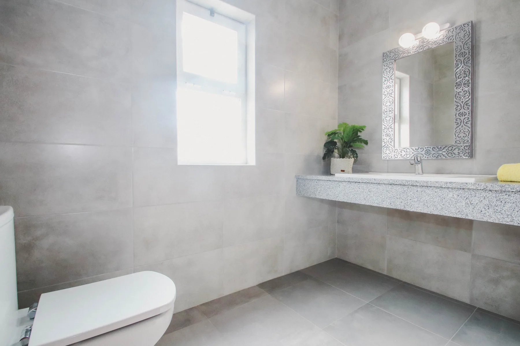 Un baño alicatado con lavabo, espejo e inodoro.