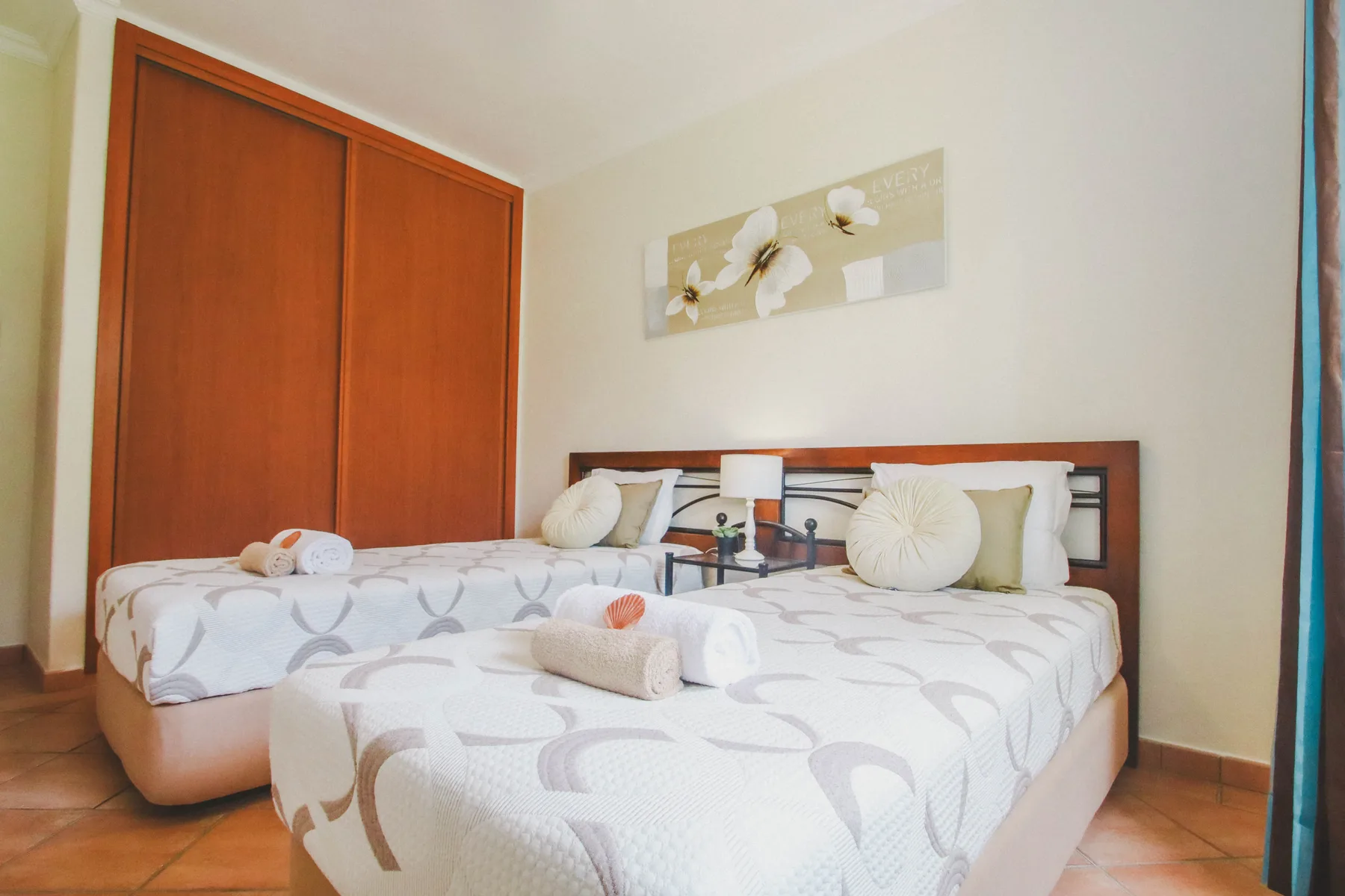Un dormitorio con dos camas, ropa de cama estampada y un cuadro en la pared.