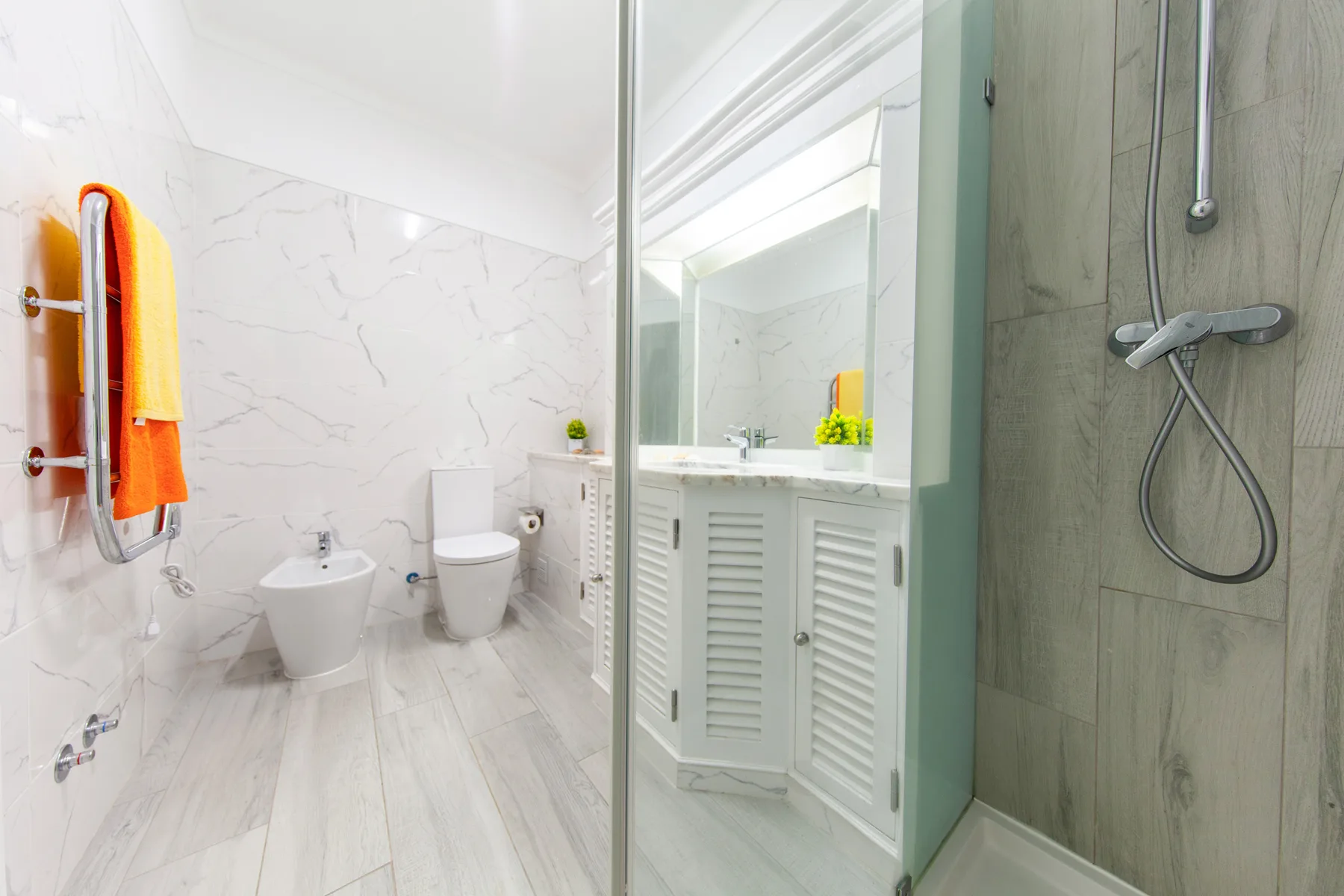 A bright bathroom with a toilet, bidet, and glass-enclosed shower.