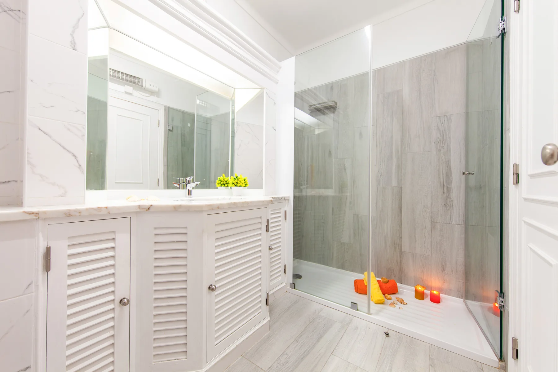 A bright bathroom with a wide vanity and glass-enclosed shower.
