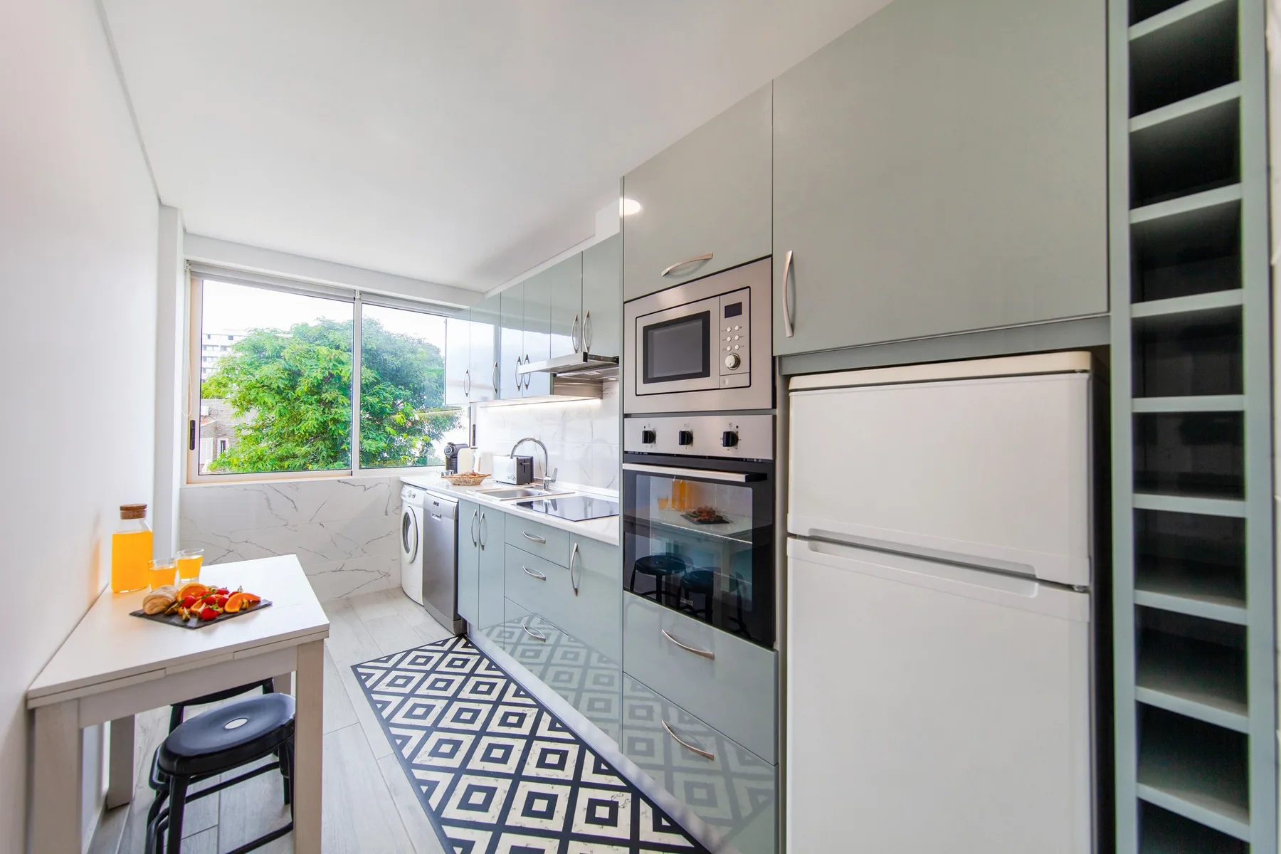A bright modern kitchen with pale cabinets and a patterned runner rug.