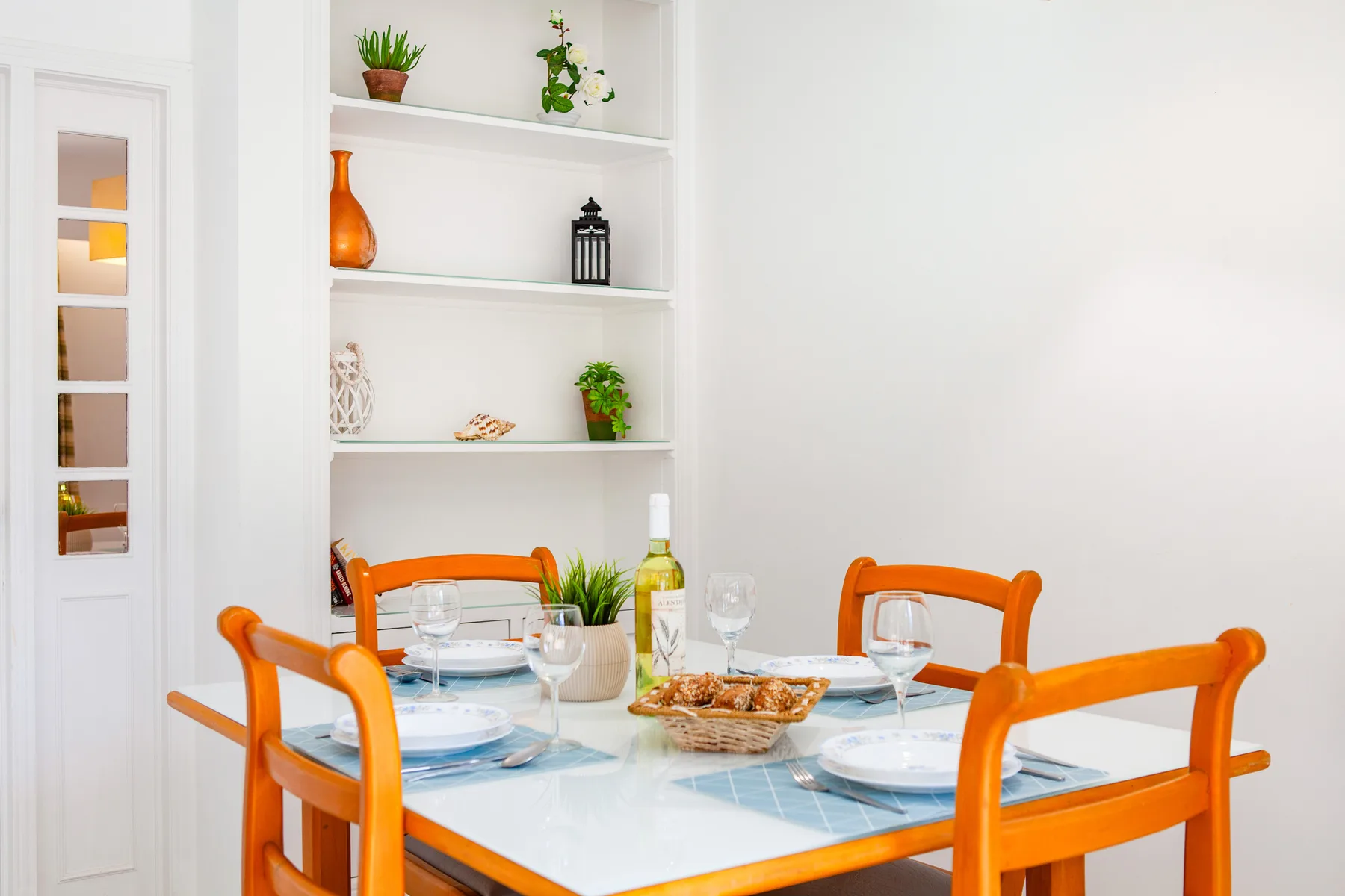 A dining area with orange seating around a glass-topped table.